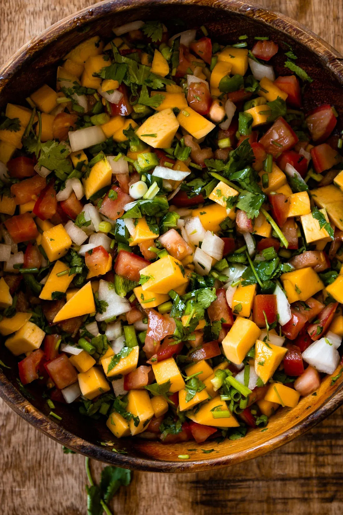 Overhead close-up of a large wooden bowl filled with freshly prepared mango salsa for Caribbean fish tacos