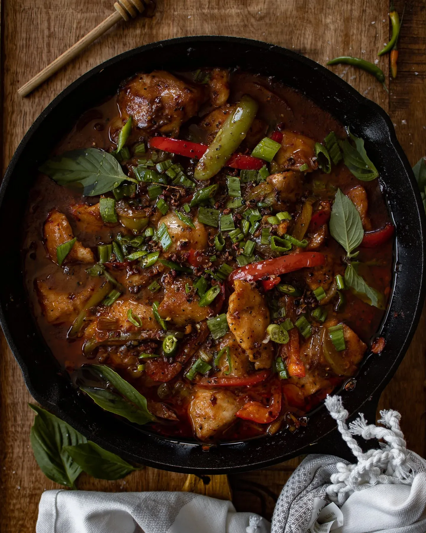 Full overhead view of cast iron Asian-inspired spicy fish showing the entire skillet packed with seasoned white fish pieces in a glistening dark red sauce