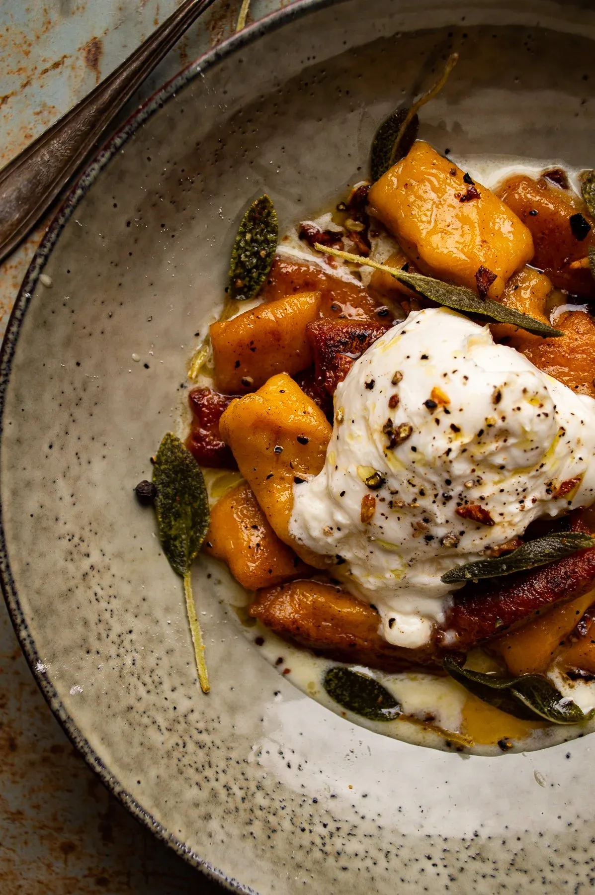 Close-in shot of a single speckled ceramic bowl of kabocha squash gnocchi with maple brown butter sauce