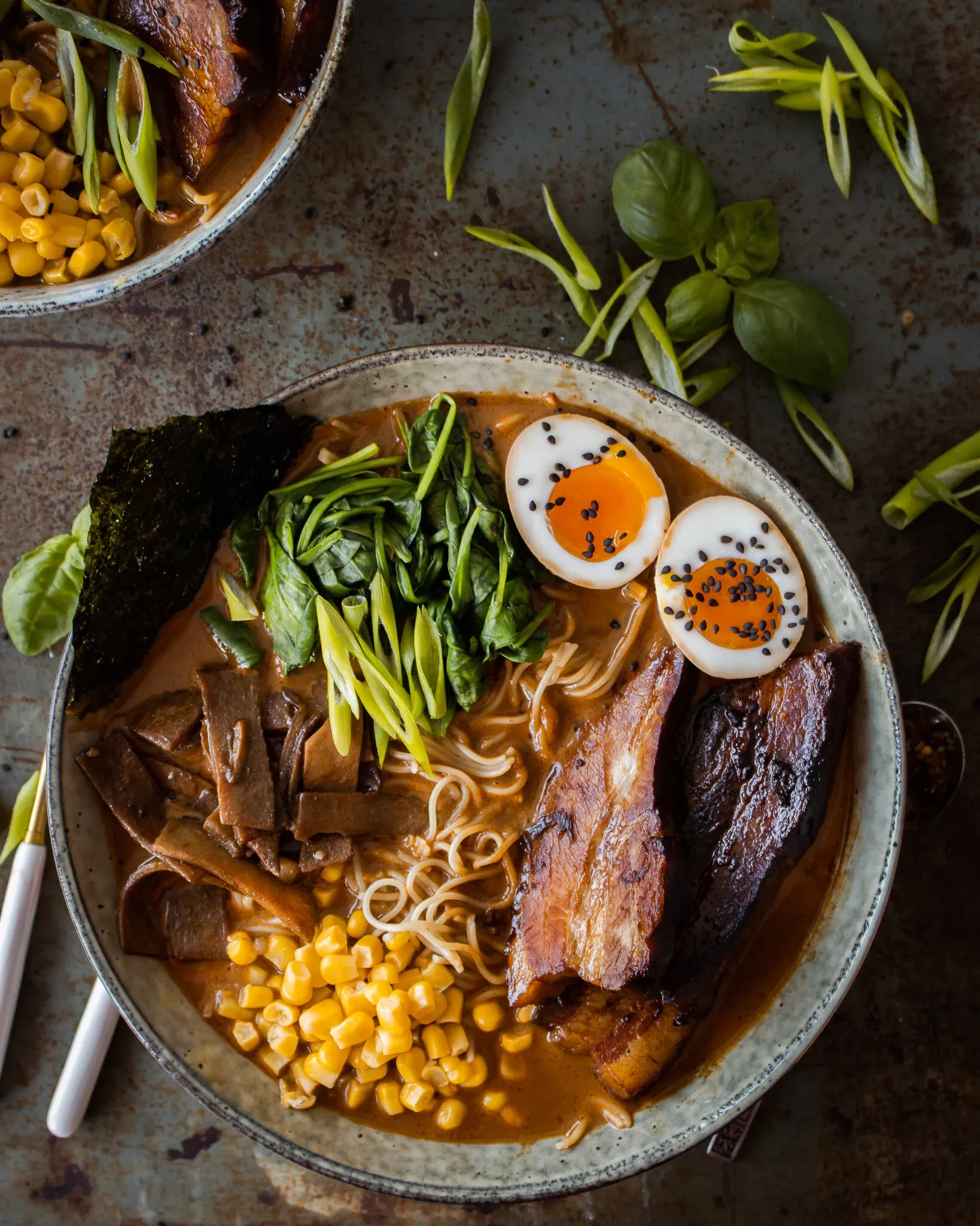 Overhead flat-lay of two bowls of Use What You Have Ramen on a dark oxidized metal surface