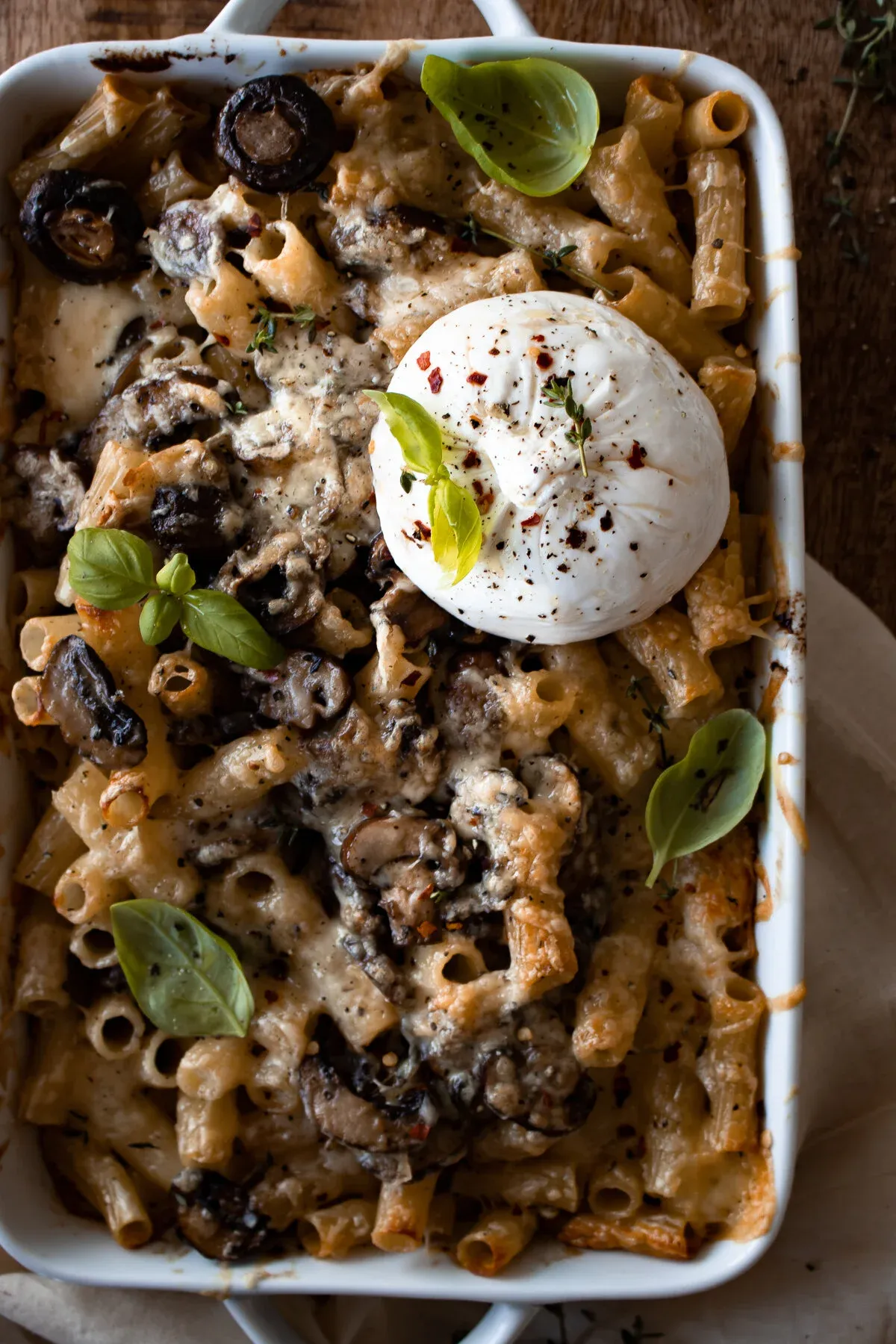 Close-up overhead view of the Baked Mushroom Pasta with Burrata dish focusing on the roasted crimini mushrooms nestled among golden baked rigatoni in creamy sauce