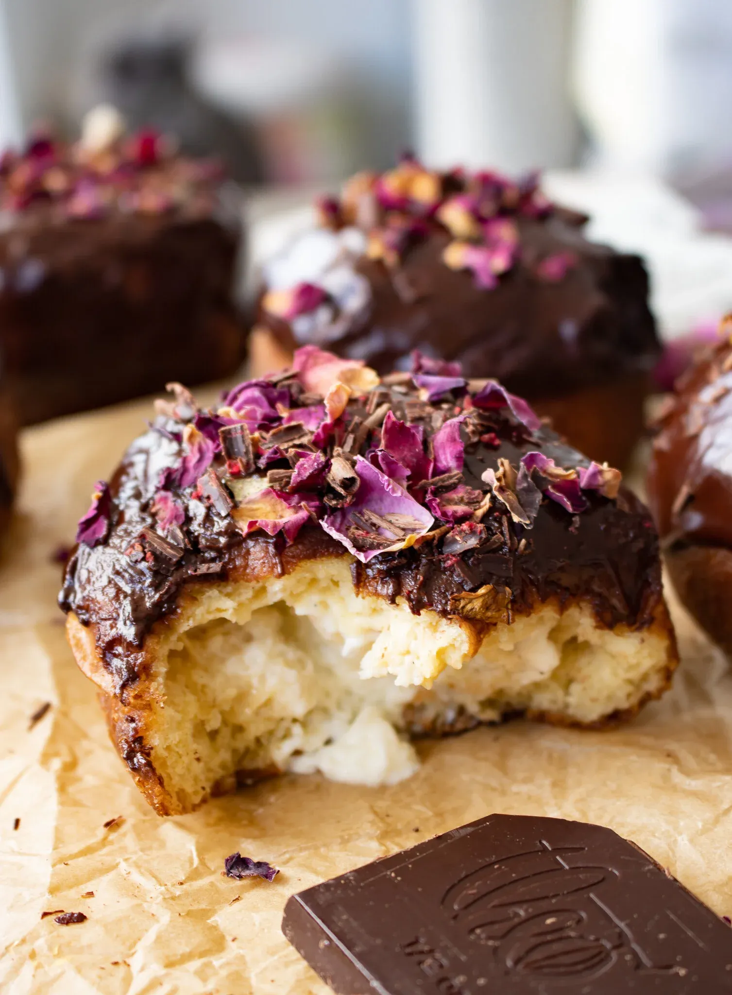Close-up angled shot of a cardamom and rose brioche doughnut torn in half on parchment paper
