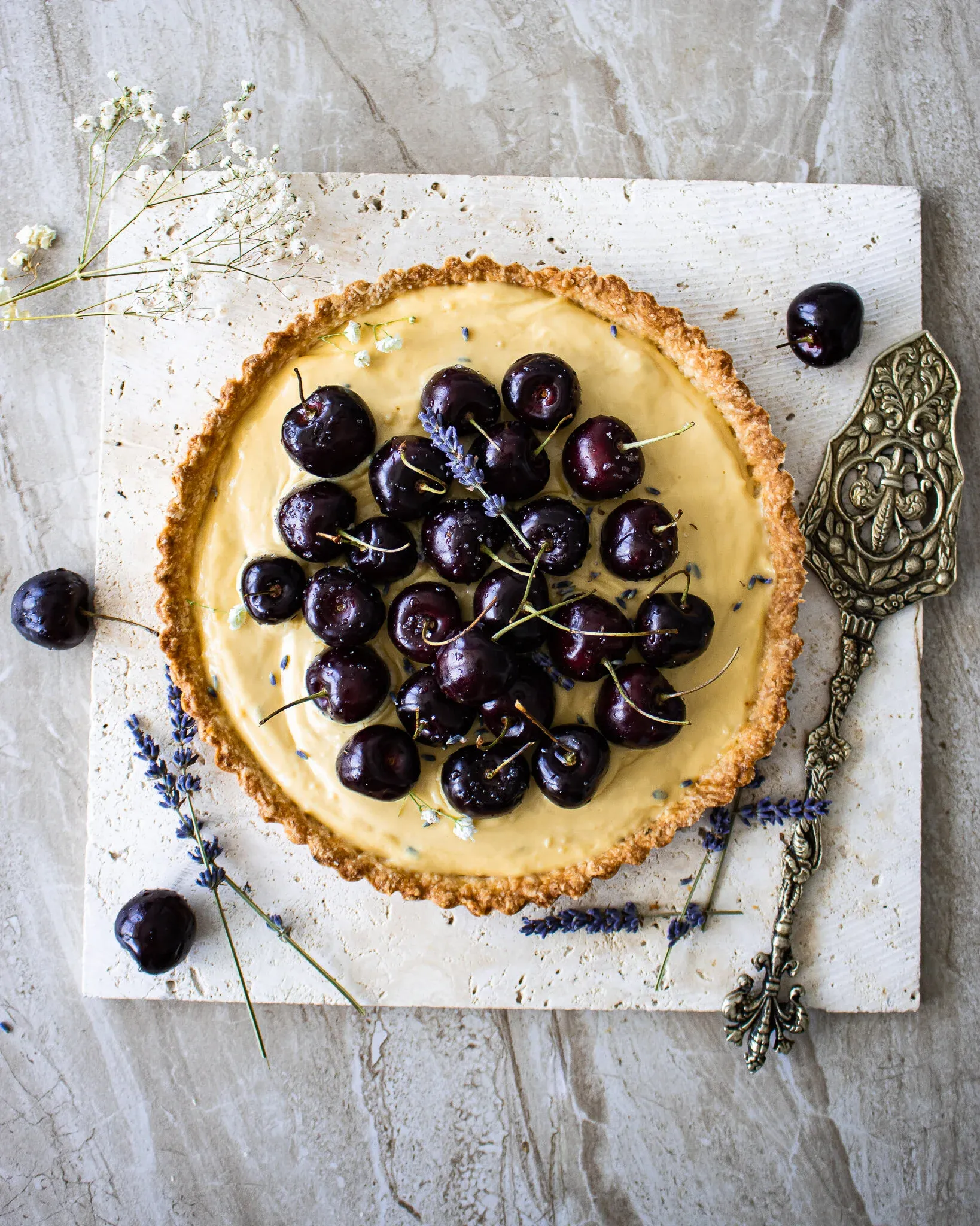 Full overhead view of the complete lavender vanilla tart centered on a square white marble slab