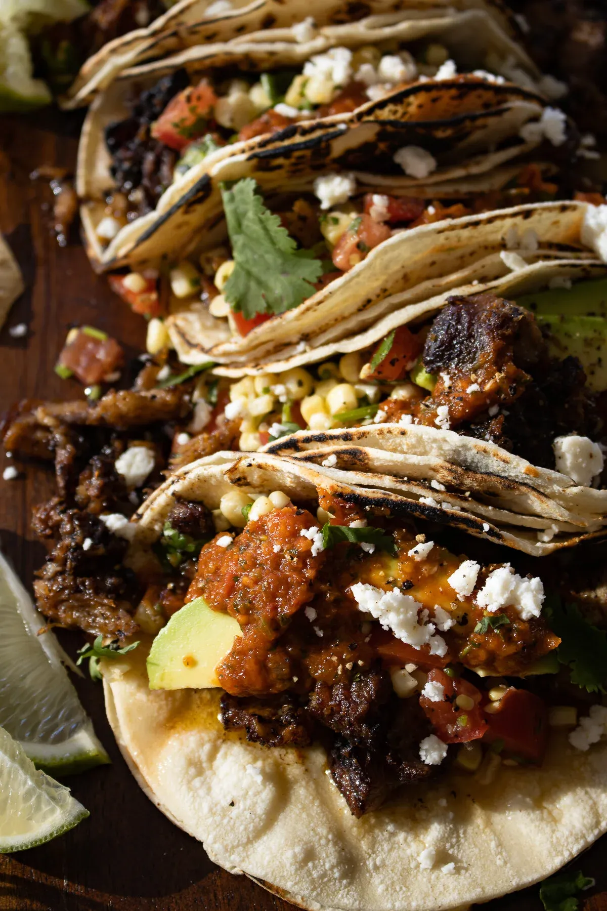 Angled close-up of three Pernil Tacos on the wooden board