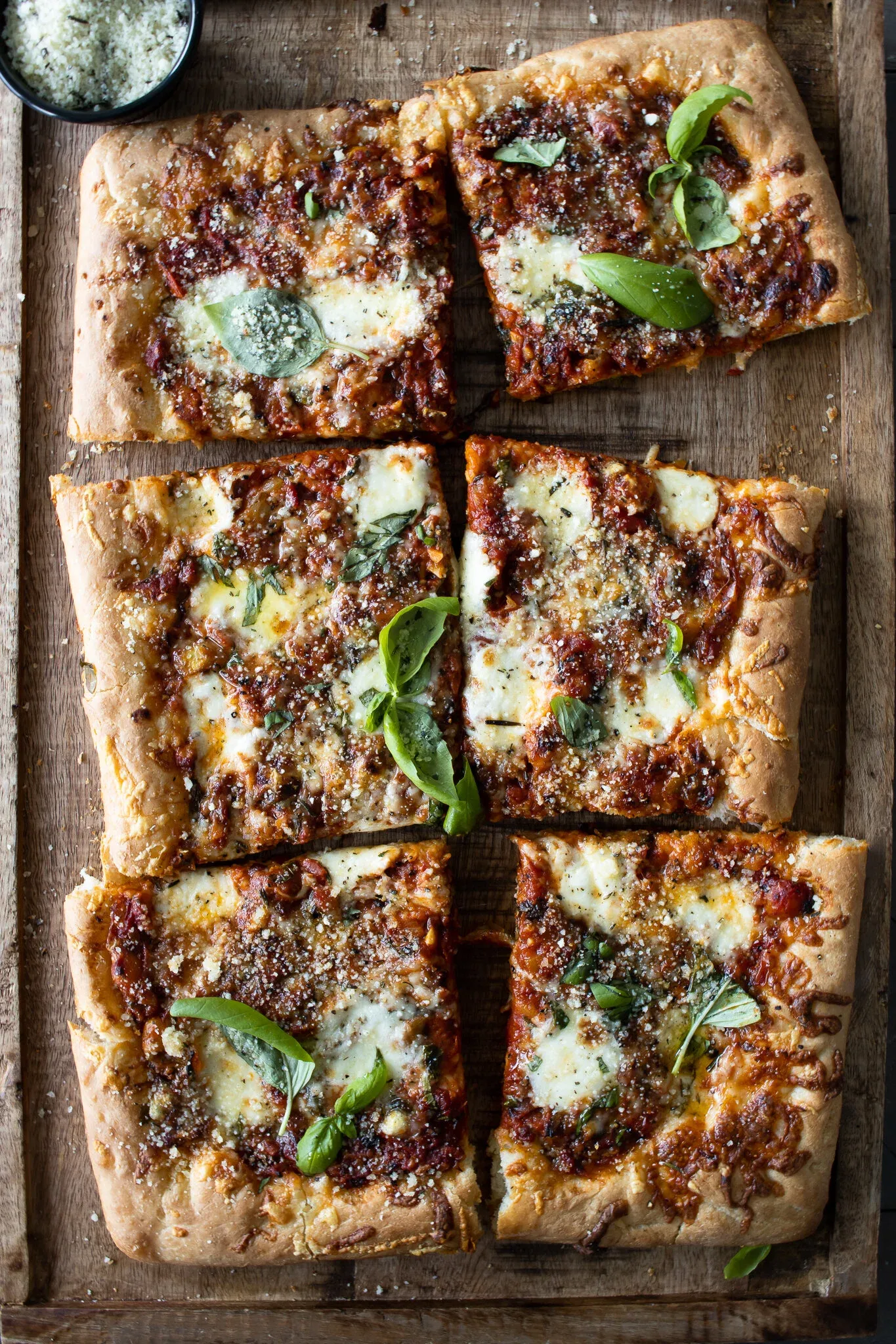 Overhead view of the Sicilian-inspired sheet pan pizza cut into six rectangular squares on the wooden board