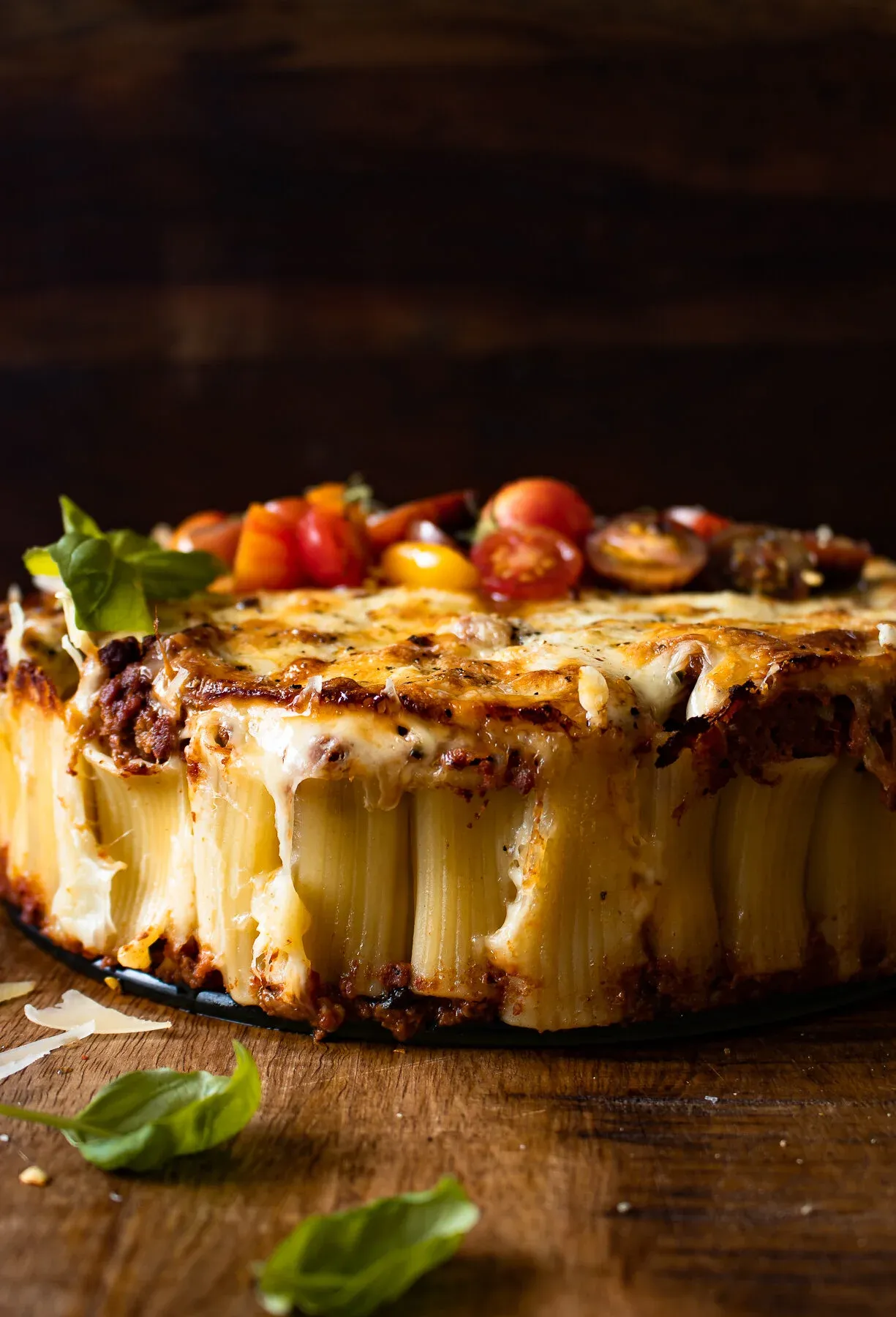 Side profile of the Rigatoni Pasta Pie lifted from its springform pan reveals tightly packed vertical rigatoni tubes filled with rich dark beef bolognese