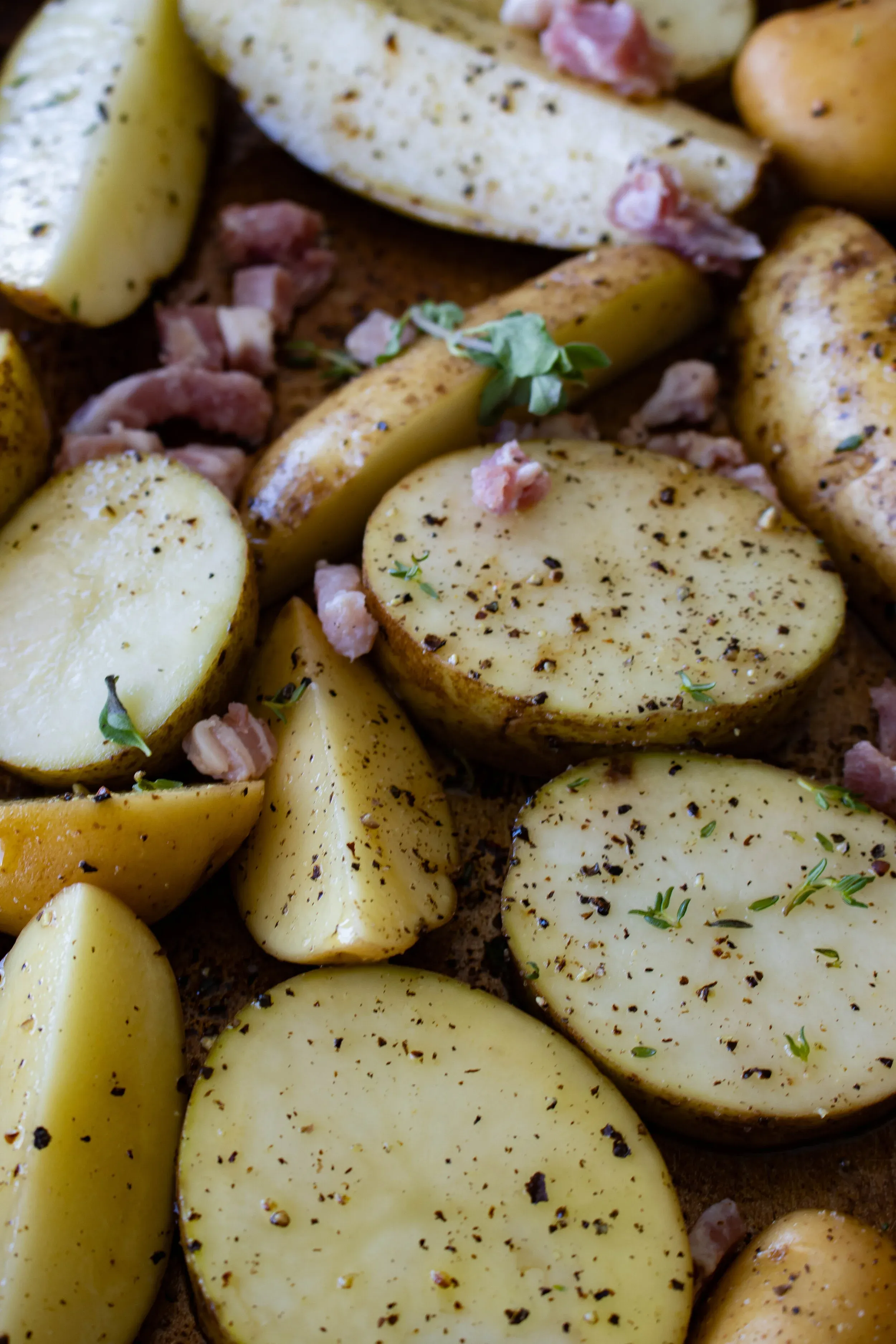 Process shot of raw halved baby potatoes and potato wedges laid cut-side up on a baking sheet