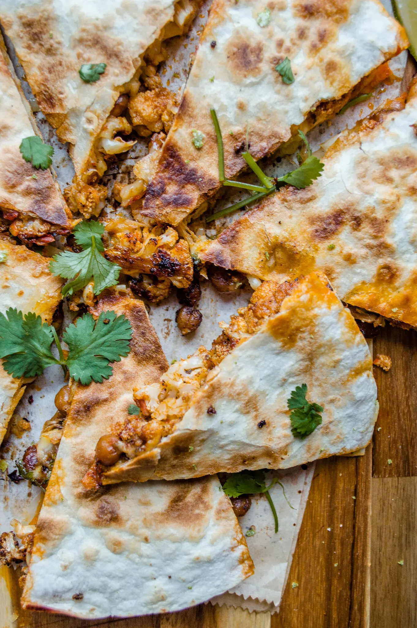 Close-up overhead shot of Crispy Chickpea and Cauliflower Quesadilla triangles fanned open on a wooden surface