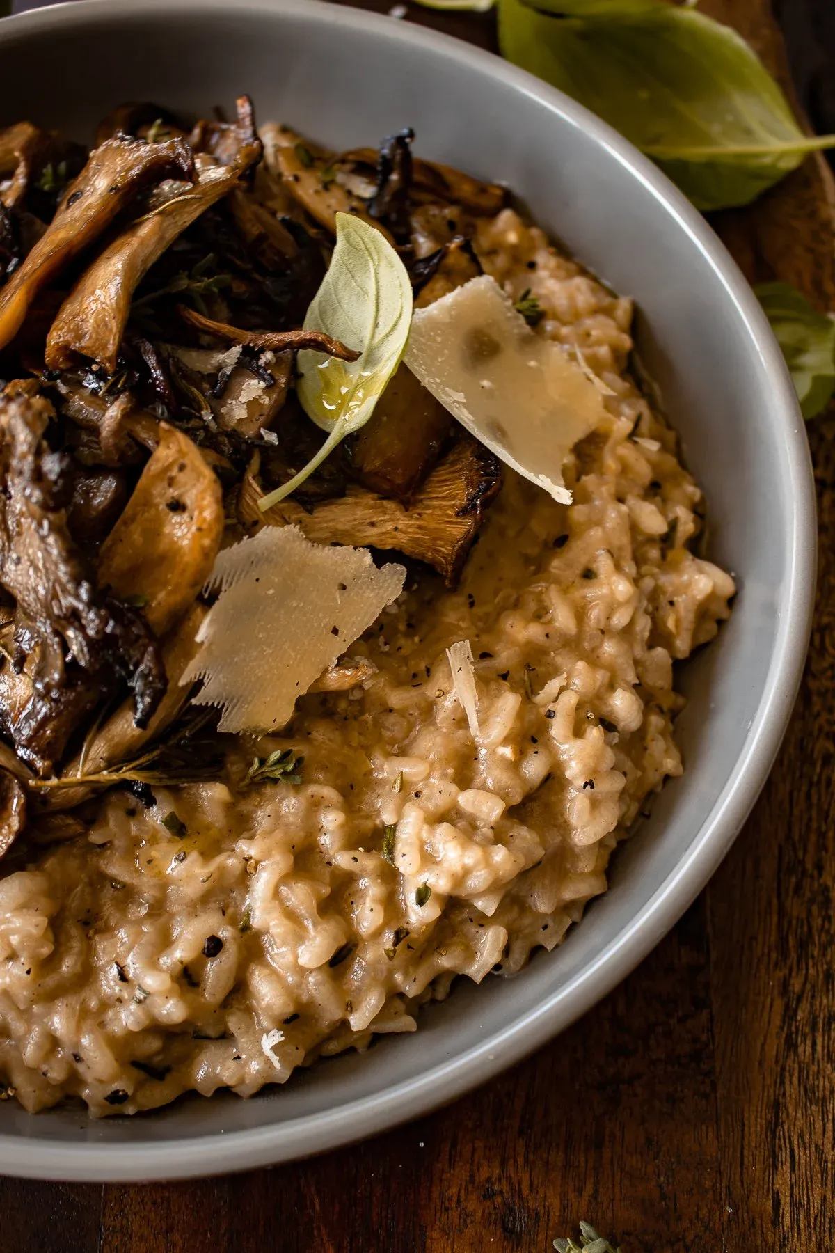 Close angled overhead crop of the gray ceramic bowl highlighting the left half of the Creamy Parmesan Risotto with Roasted Thyme Mushrooms