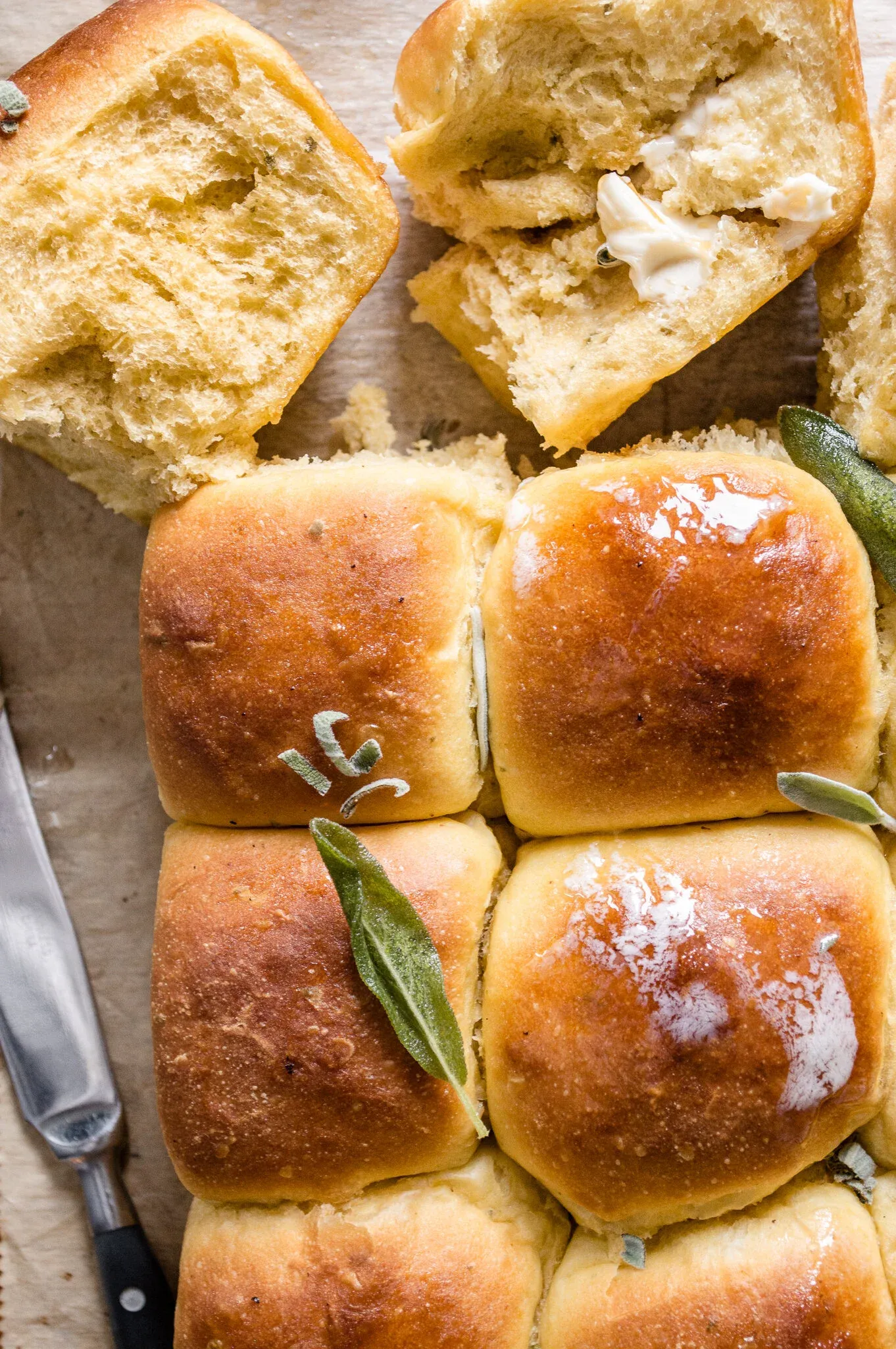 Close-up overhead of pumpkin fried sage honey bread rolls on parchment