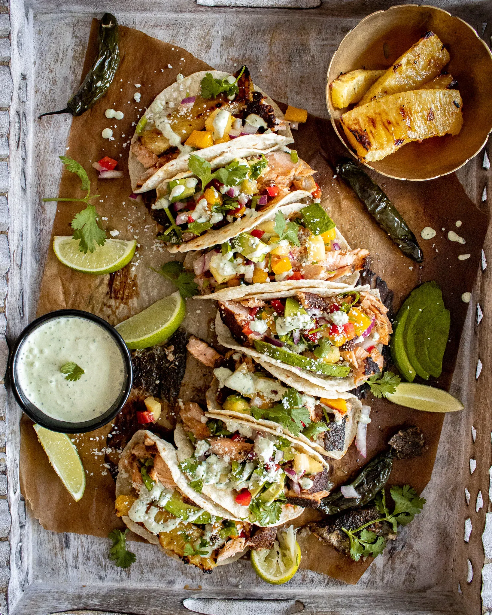 Top-down perspective of Blackened Salmon Tacos with Grilled Pineapple and Mango Salsa on a rustic whitewashed wood tray