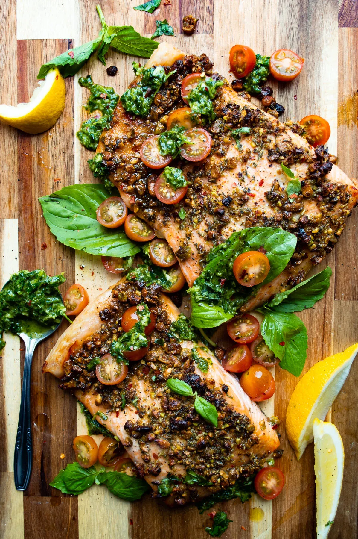 Directly overhead view of two large pistachio-crusted salmon fillets side by side on a butcher block cutting board