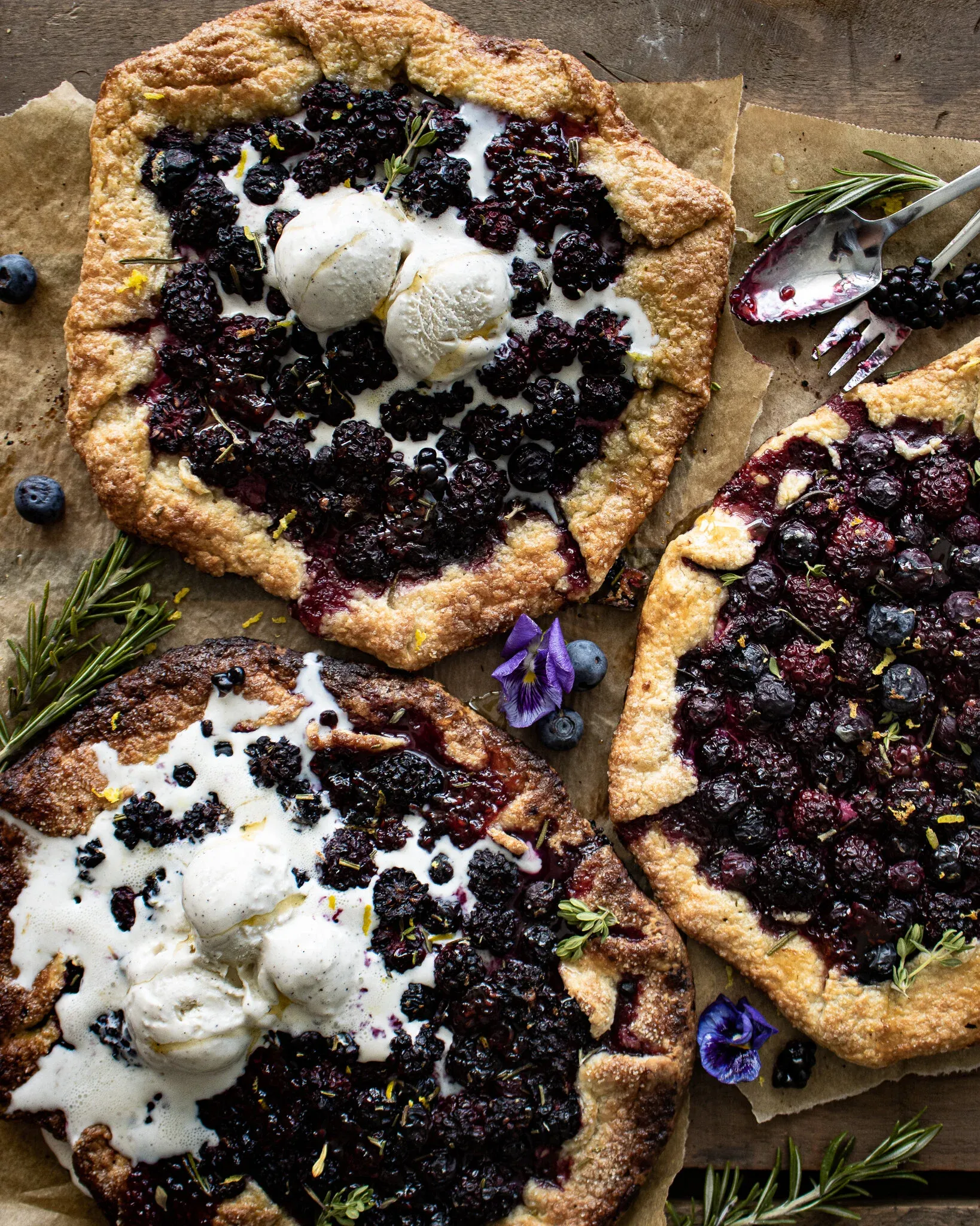 Three Berry Galettes with Honey Goat Cheese arranged on parchment-lined wood