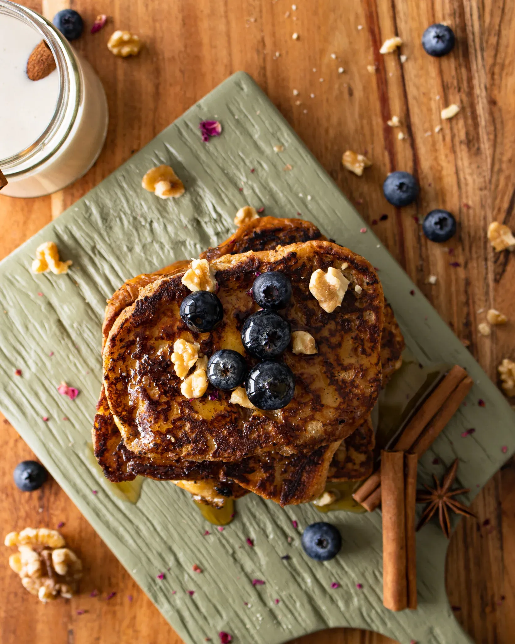 Overhead flat-lay of the Coquito French Toast stack on a sage-green cutting board on a warm wood table