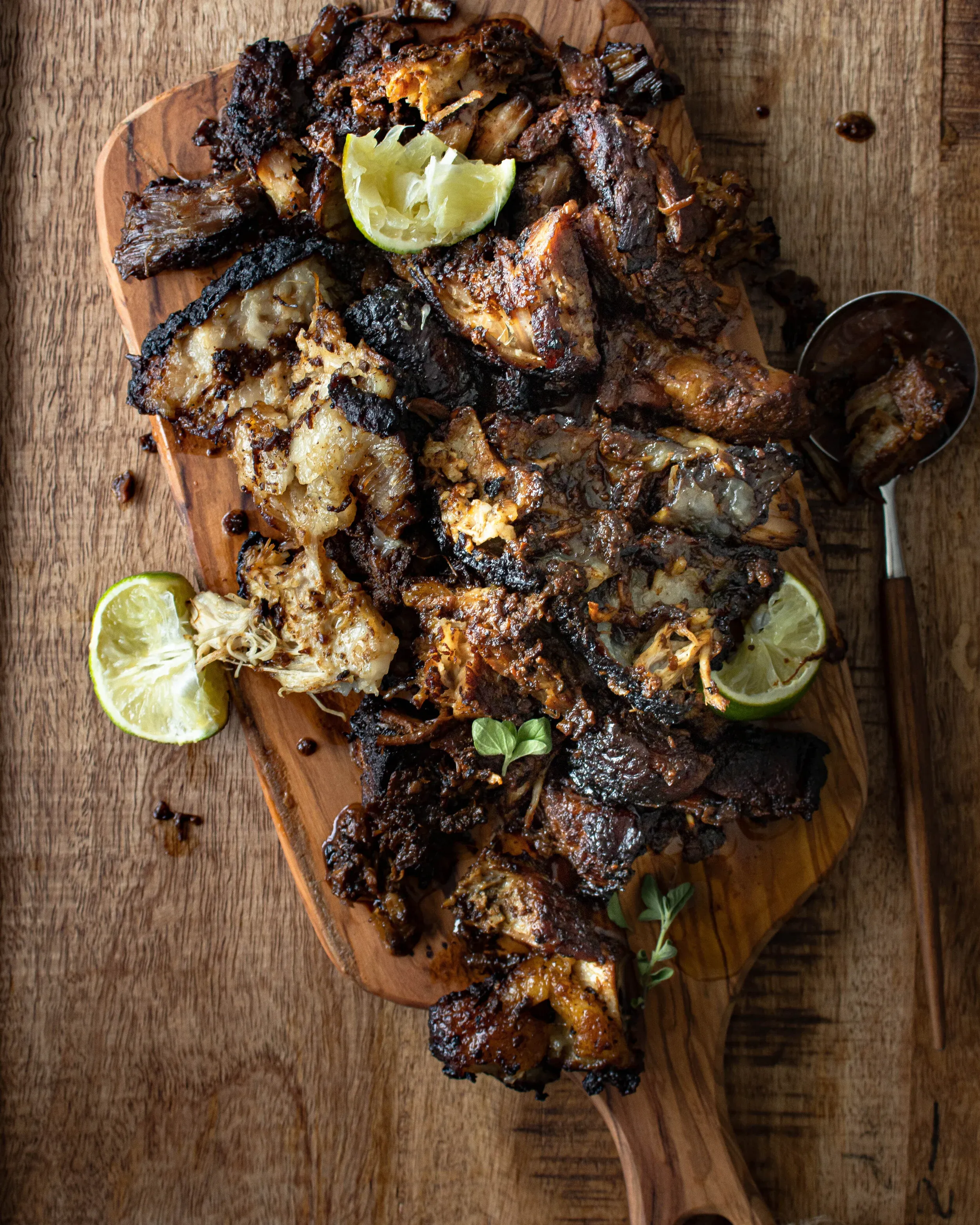 Overhead shot of pulled and broken-apart puerco asado roast pork piled on an oval wooden cutting board