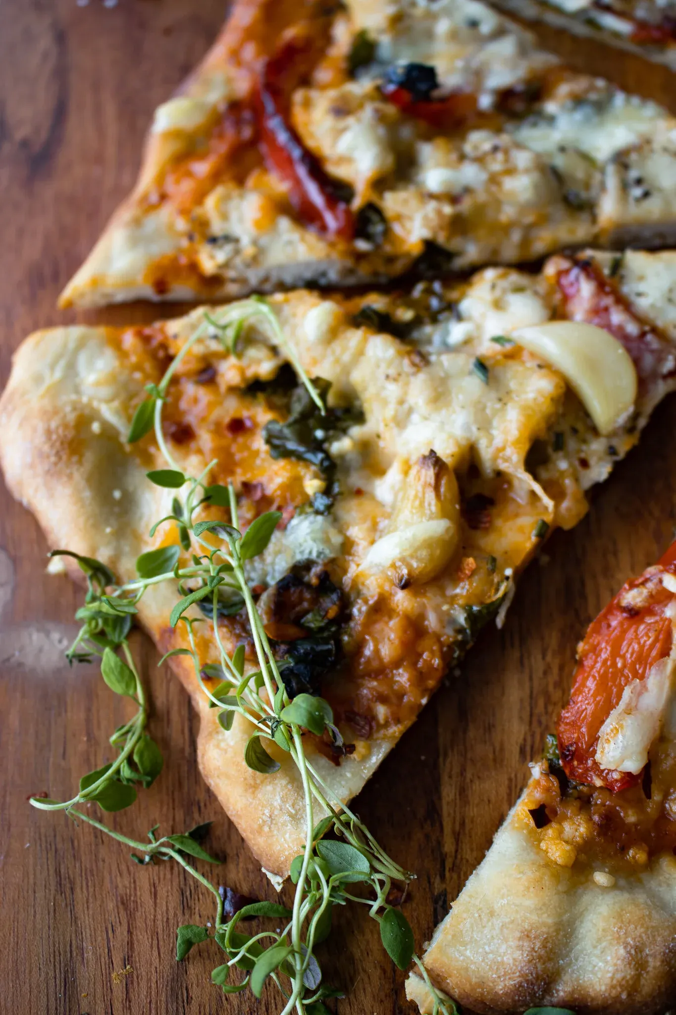 Angled close-up of two slices of chicken alla vodka pizza on a wooden board, the golden puffed crust prominent
