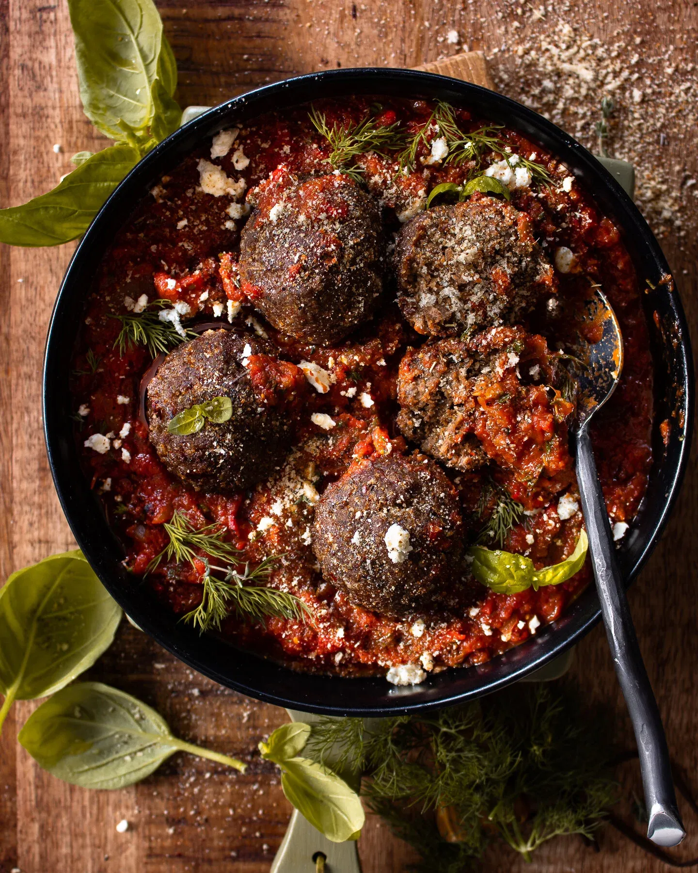 Top-down shot of the finished meatballs with spicy tomato sauce in a black skillet