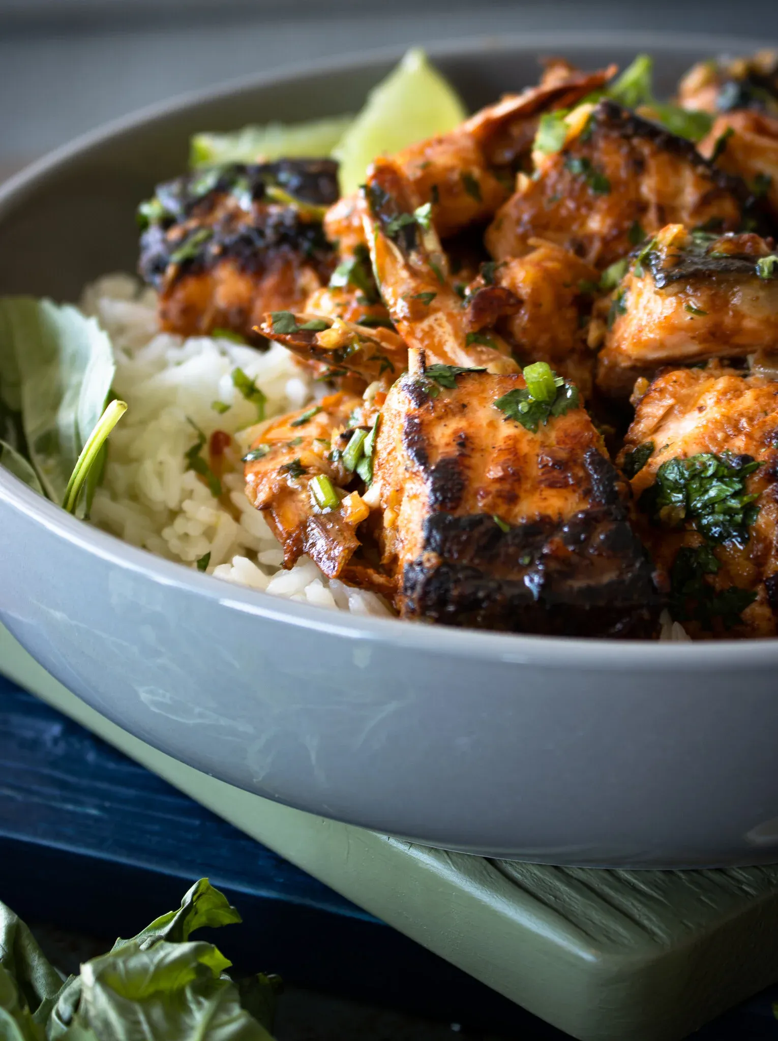 Low side-angle view of the gray bowl of Honey Garlic Salmon and Shrimp Bowl showing the charred and herb-glazed salmon cubes and shrimp piled high over white rice