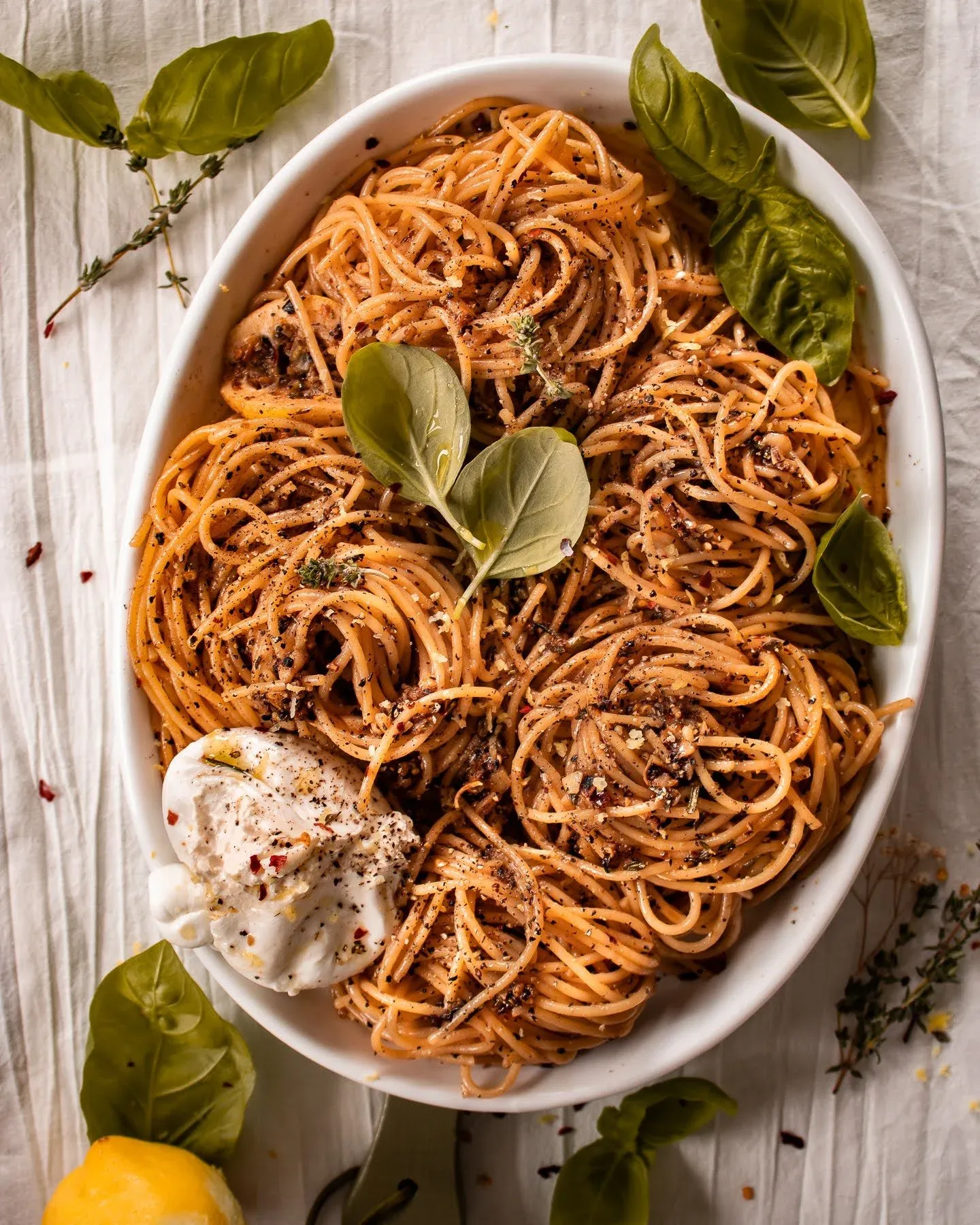 Overhead of the complete lemon pepper pasta with burrata in a white oval dish without the chicken