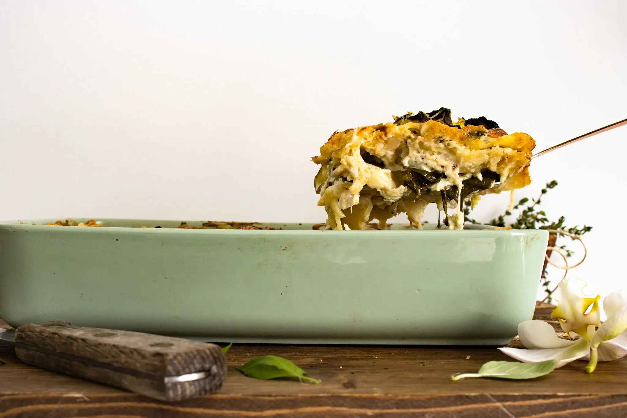 Side view of a spatula lifting a cheesy slice of Spinach