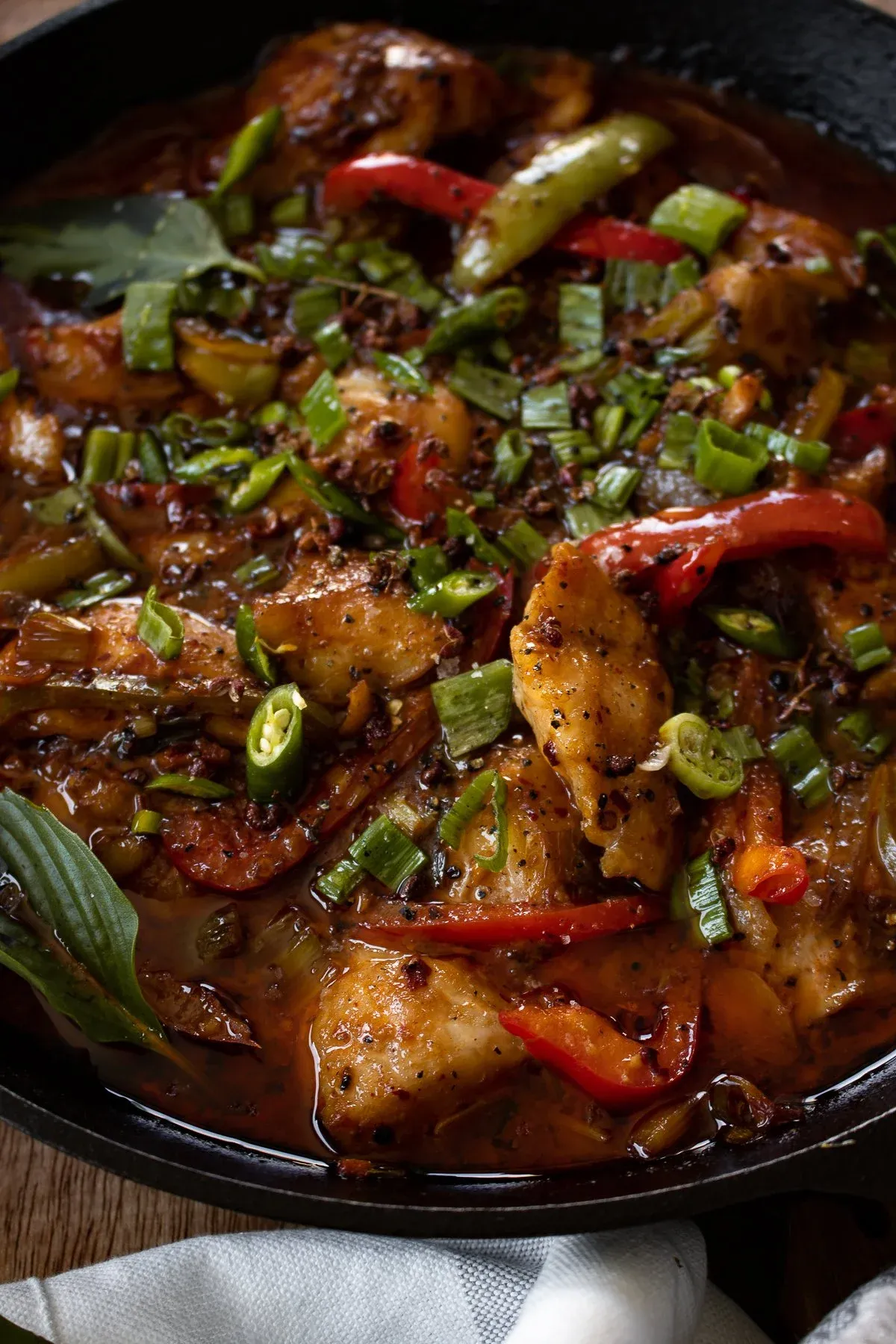 Angled close-up of cast iron Asian-inspired spicy fish from slightly below overhead