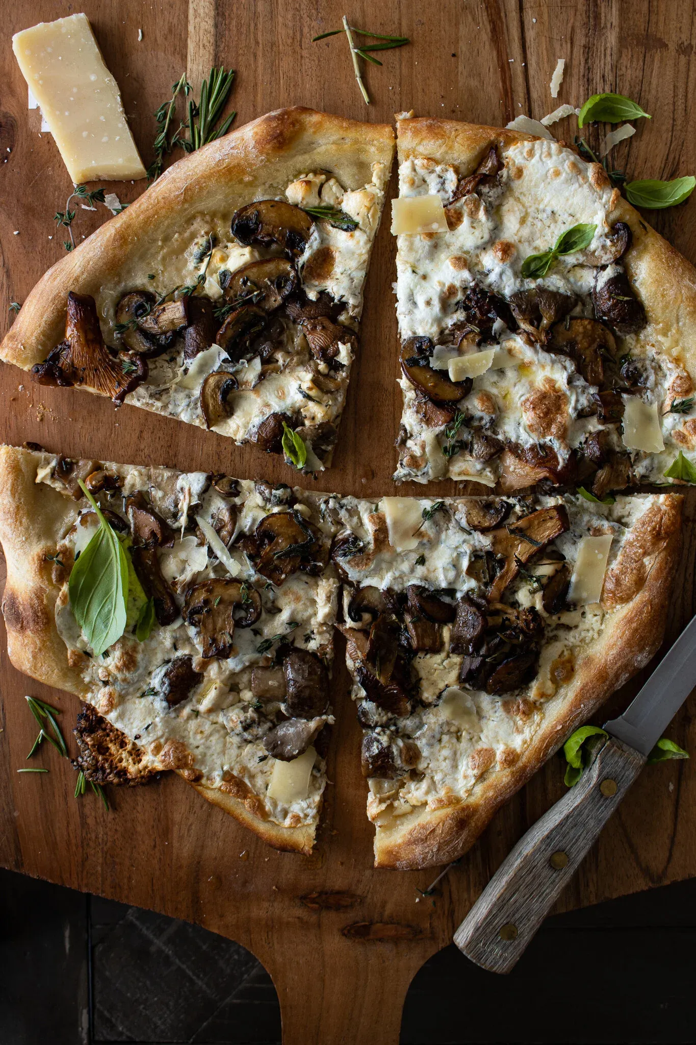 Overhead shot of the Mushroom and Goat Cheese Pizza sliced into quarters on the wooden pizza peel