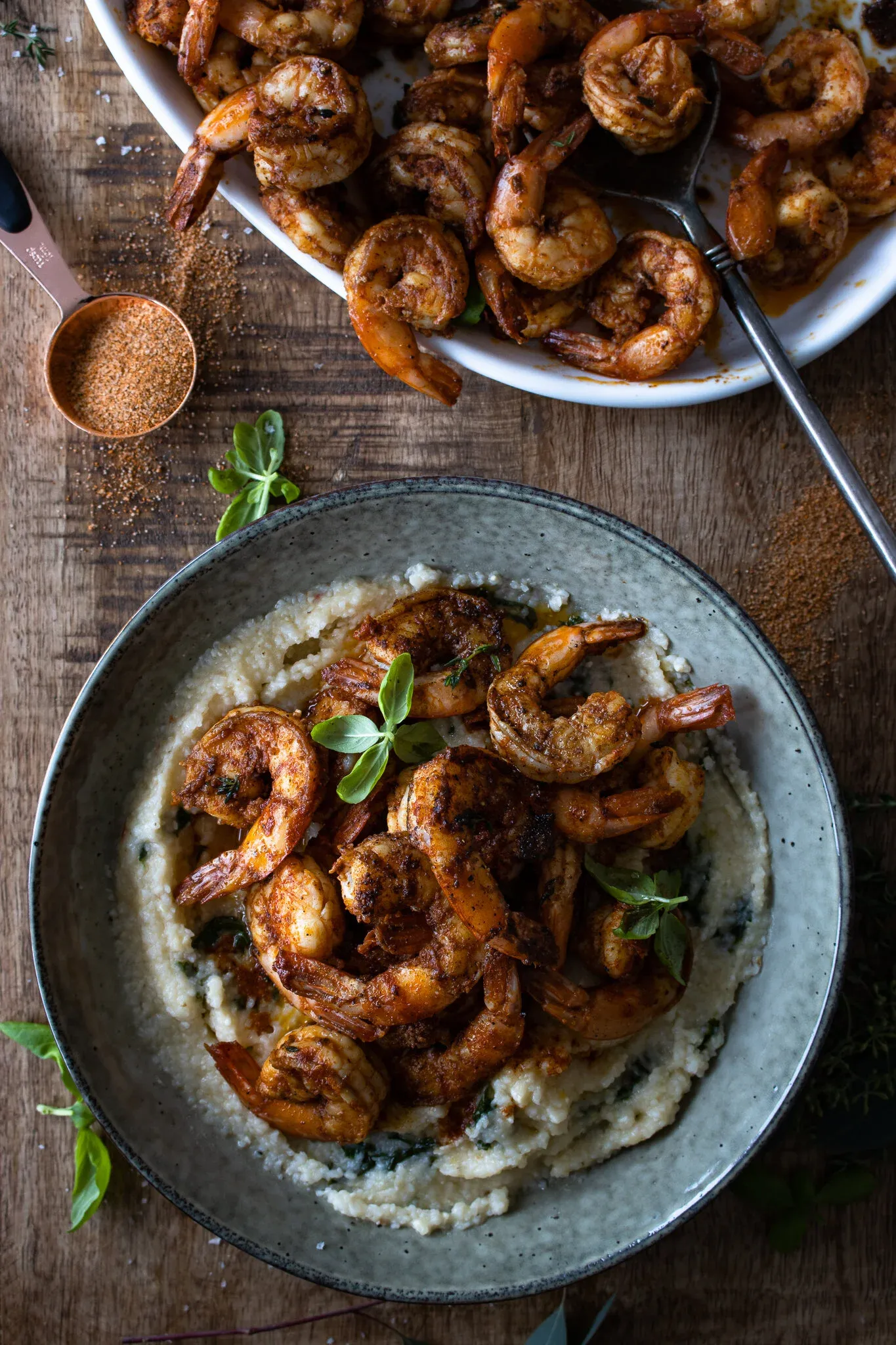 Overhead view of a plated serving of Cajun Shrimp with Kale Polenta in a rustic blue-gray ceramic bowl