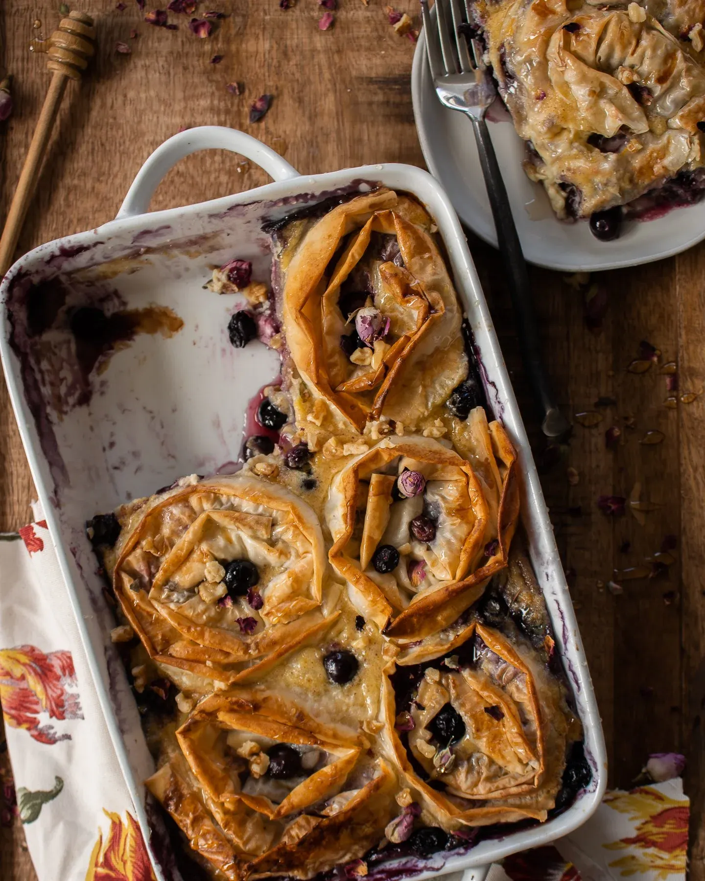 Overhead angled view of Blueberry Phyllo Milk Pie with one serving already removed onto a white plate at upper right with a fork