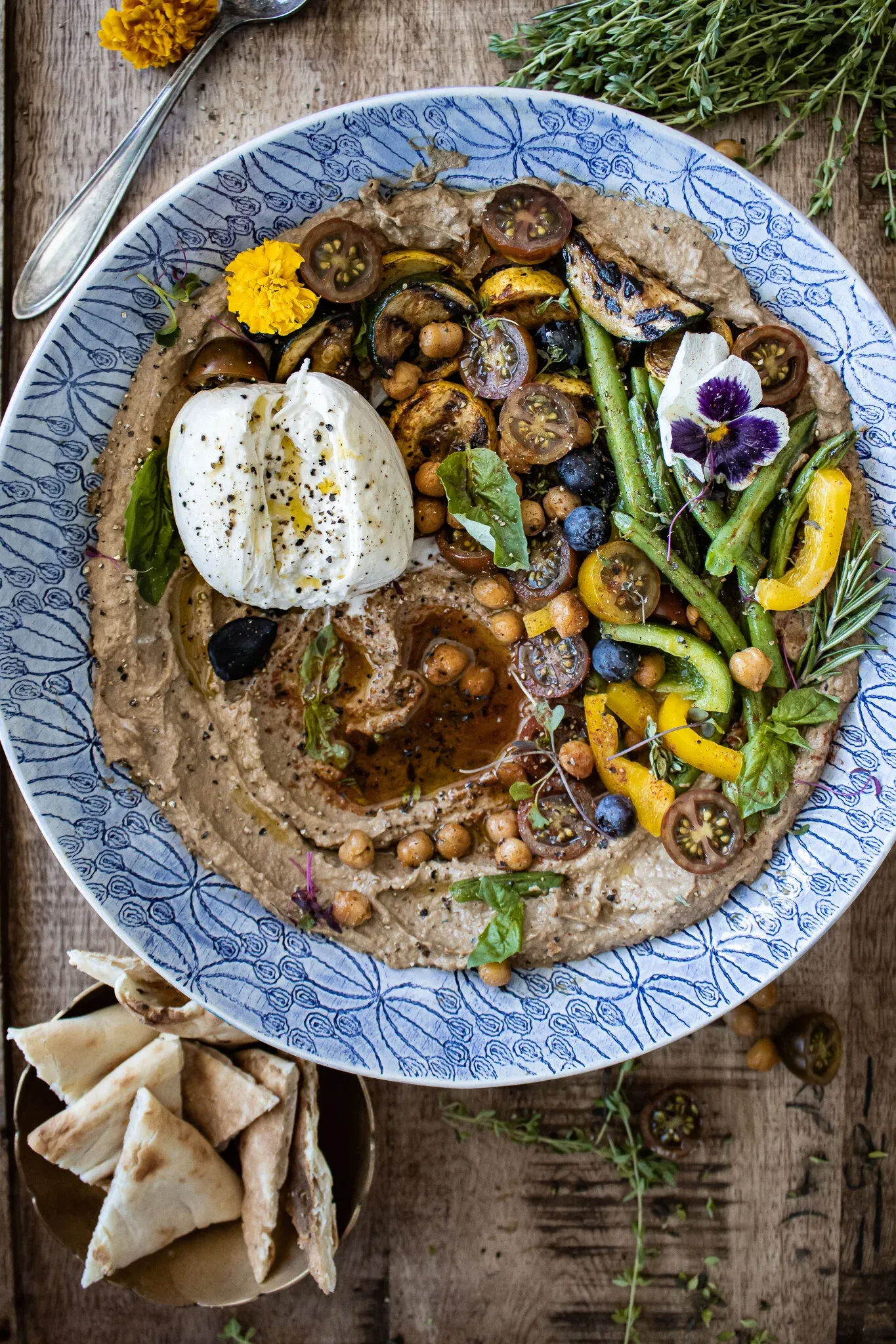 Top-down shot of the full Black Garlic Hummus Platter with Summer Veggies and Burrata in a blue-and-white ceramic bowl
