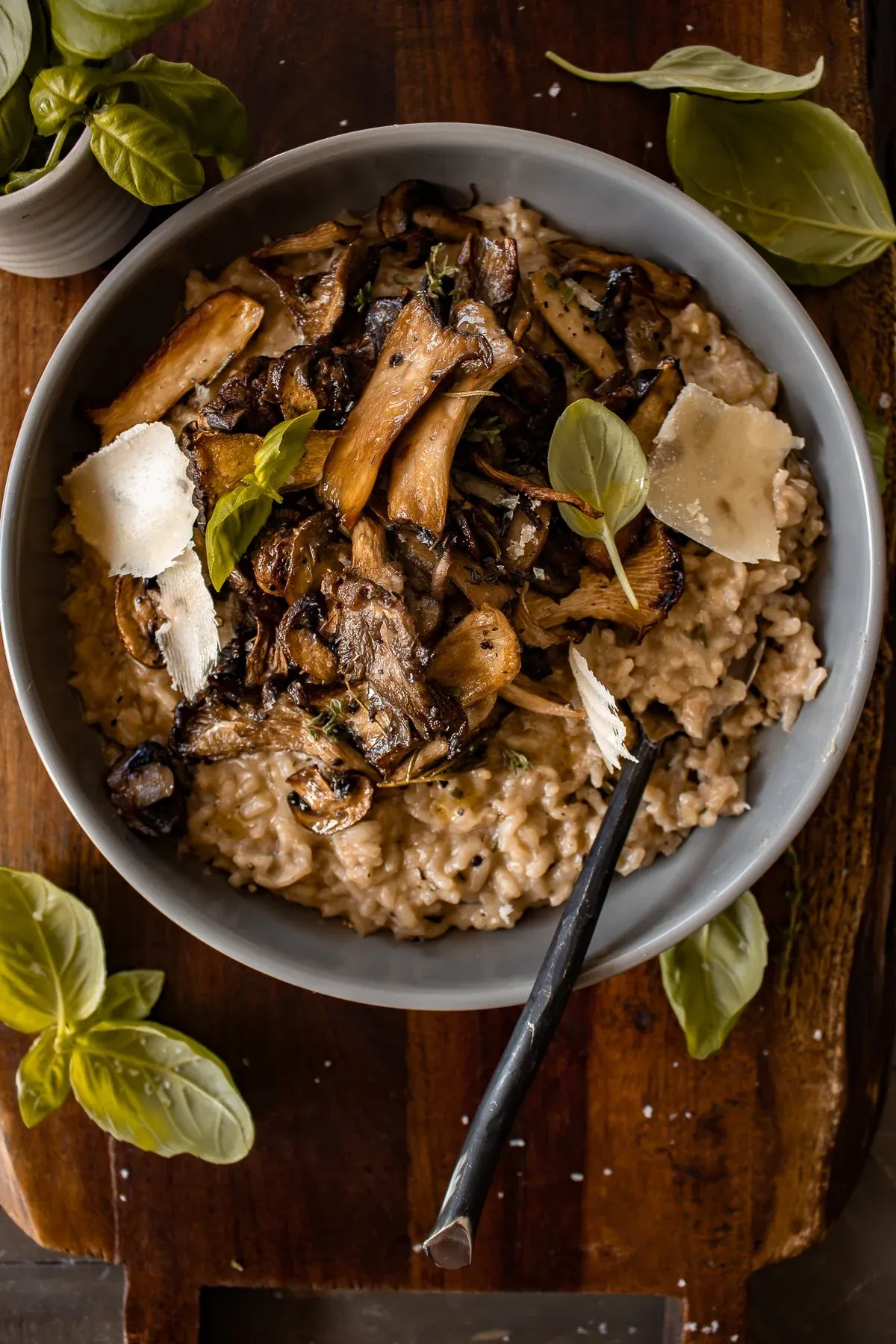Overhead shot of the gray bowl of Creamy Parmesan Risotto with Roasted Thyme Mushrooms on the dark wood board
