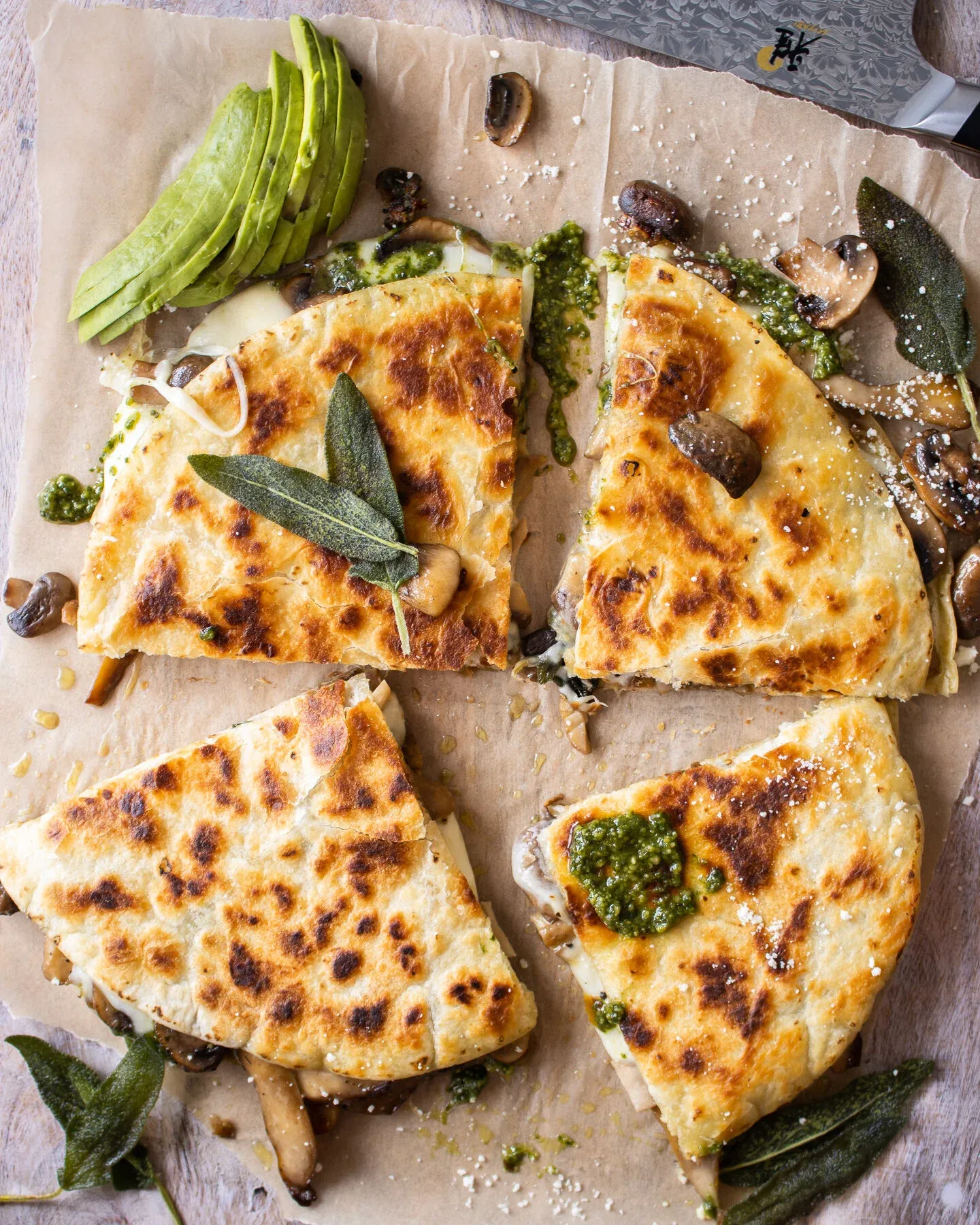 Overhead flat-lay of the Wild Mushroom and Pesto Quesadilla cut into four triangular wedges and fanned open on parchment paper