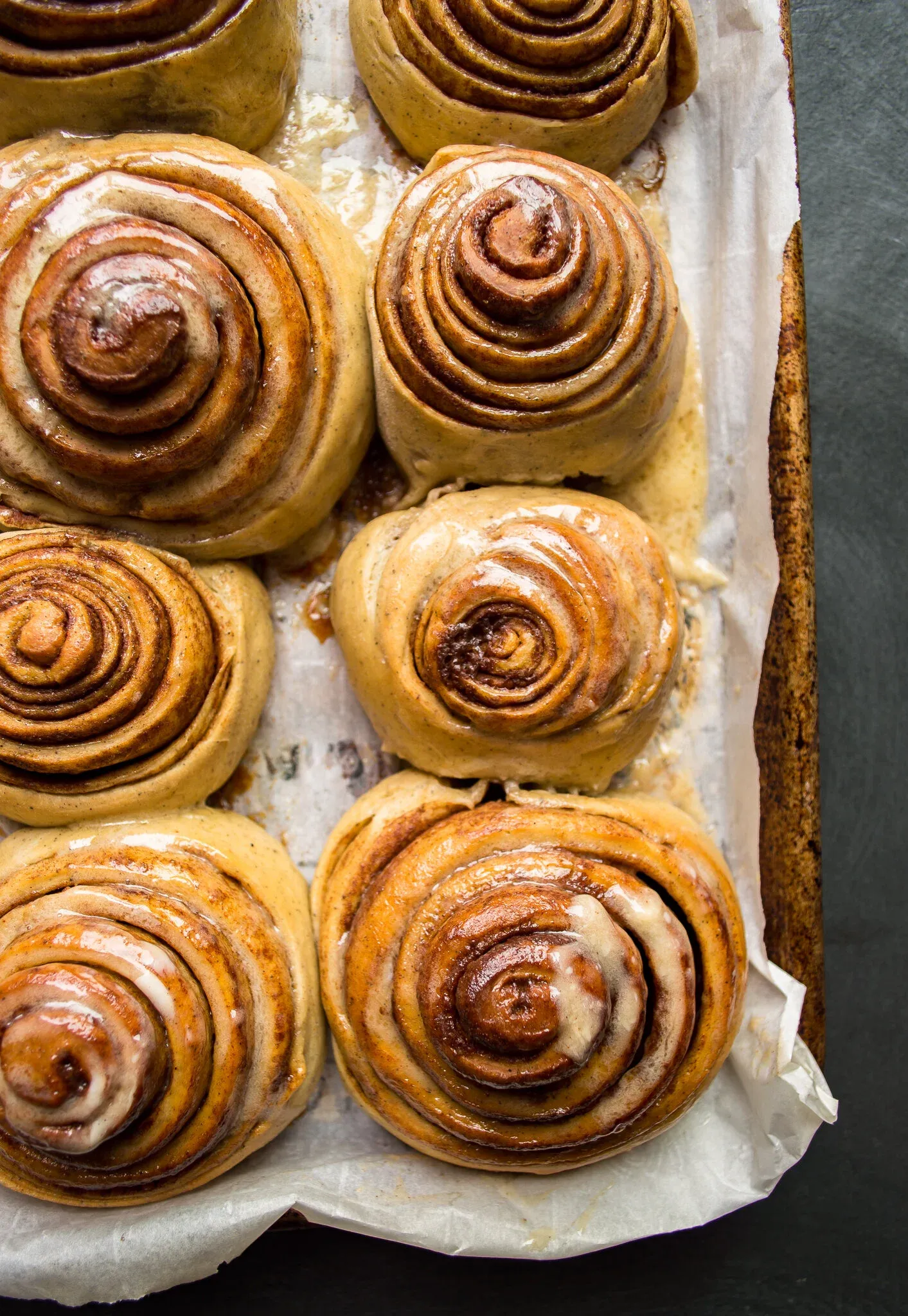 Angled overhead view looking down into the corner of the baking pan showing six Cinnamon Rolls with Honey Mascarpone Icing