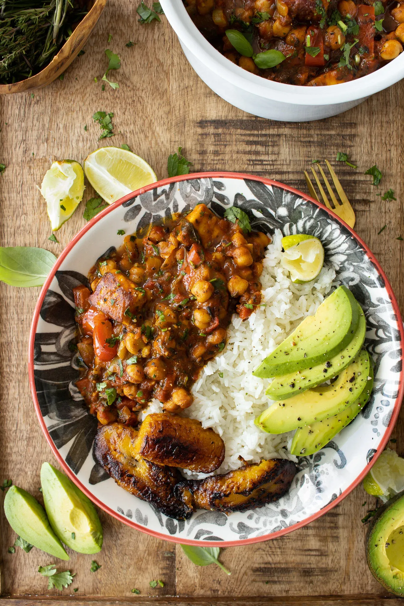 Flat-lay overhead of a full plated serving of Vegetarian Chickpea and Paneer Picadillo in the black floral bowl on a rustic wood board