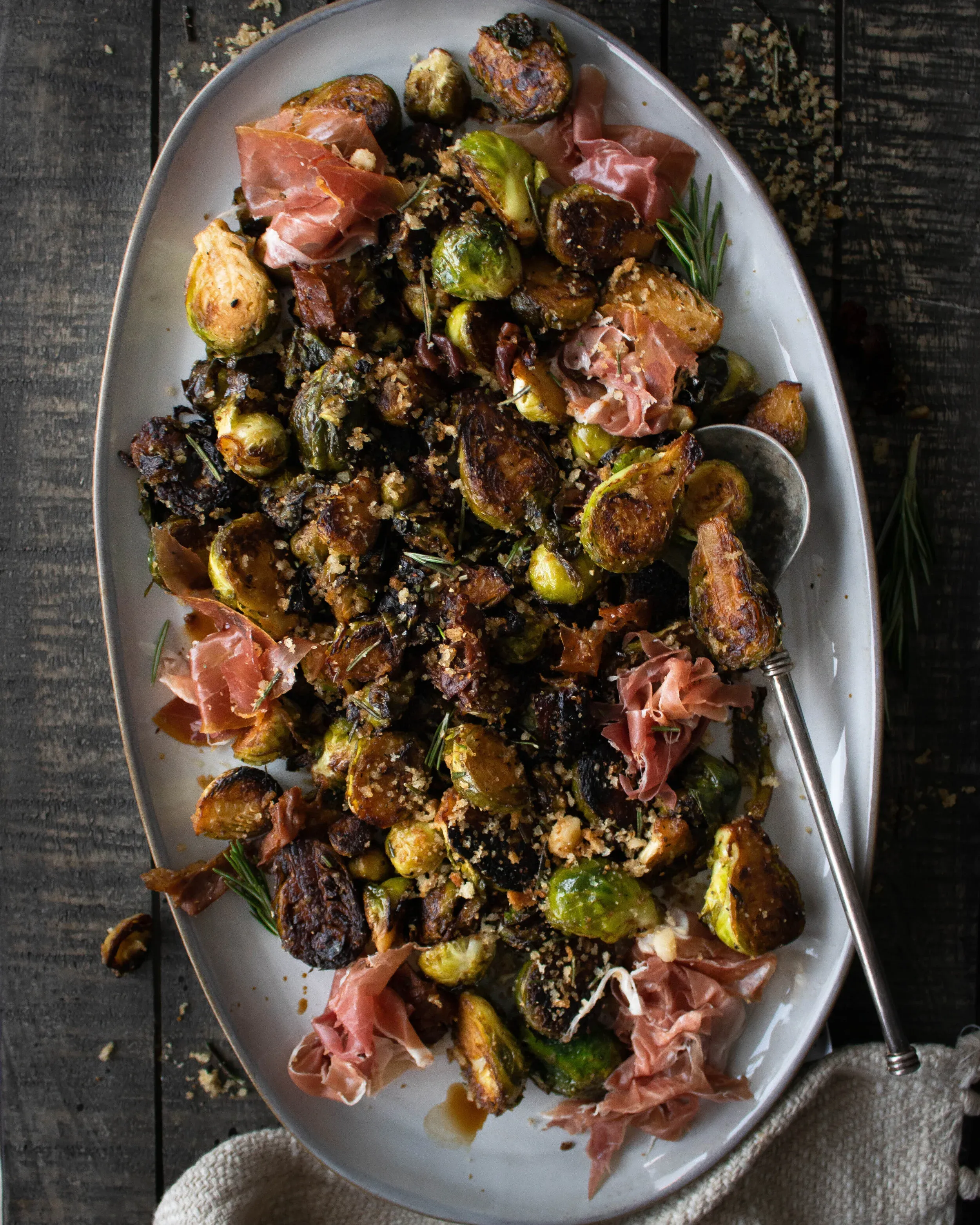 Full overhead view of the pan-fried Brussels sprouts and prosciutto platter on dark wood