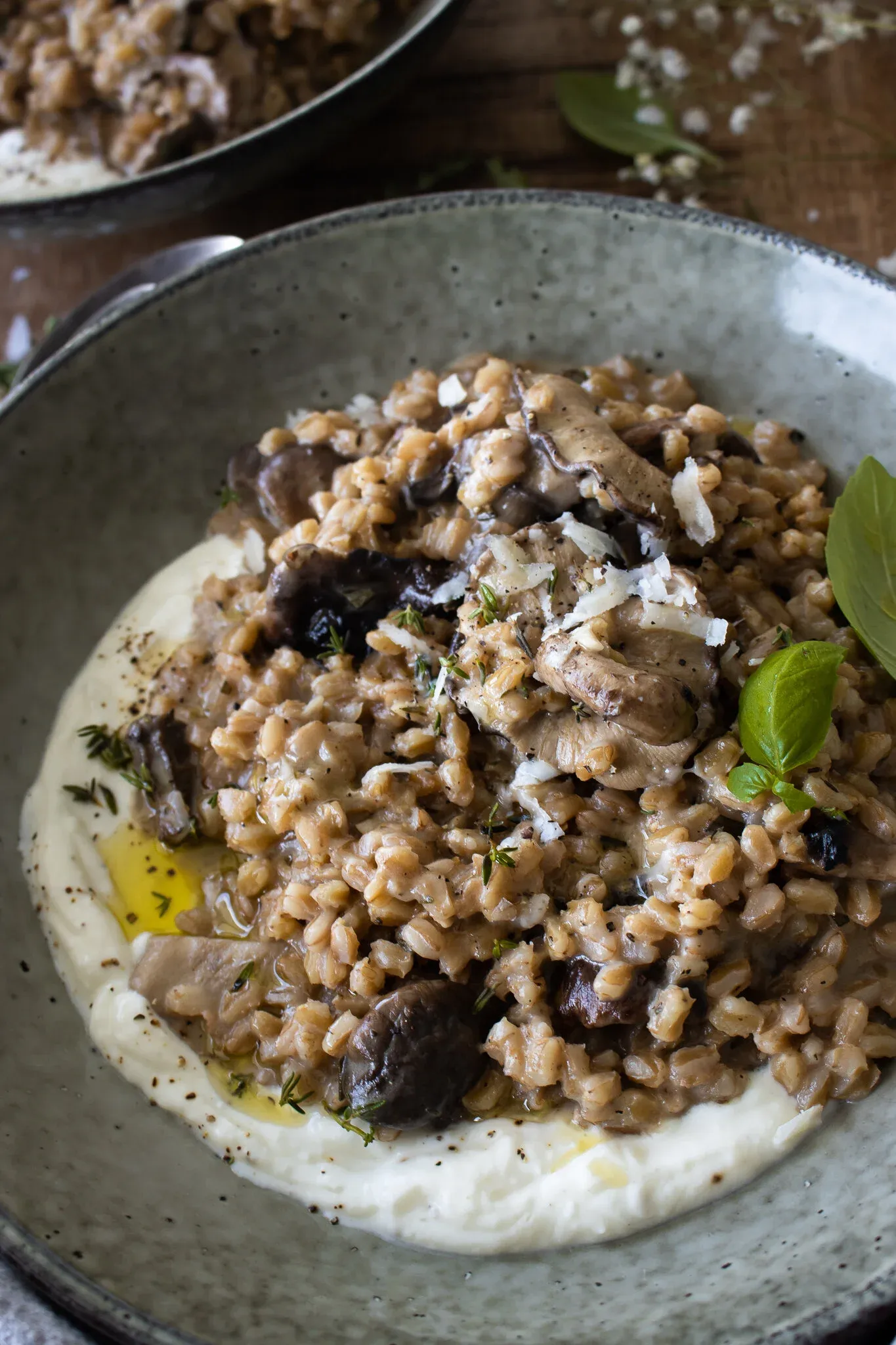 Three-quarter close-up of a grey speckled bowl filled with Farro Risotto with Mushrooms and Whipped Ricotta