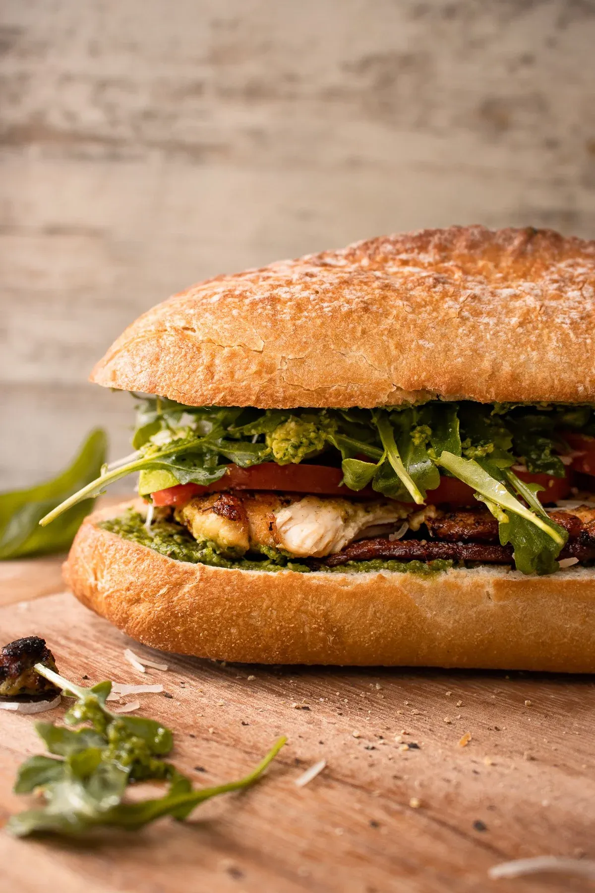 Angled profile shot of the whole uncut pesto chicken BLT on ciabatta from a slightly lower angle