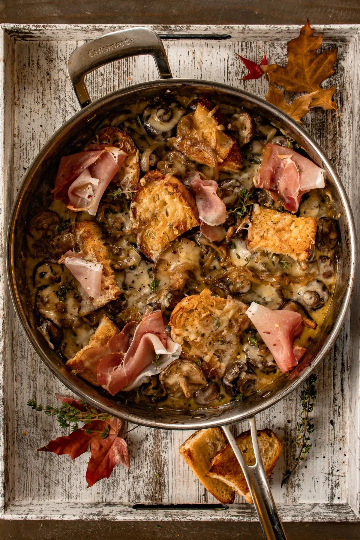 Full overhead flat-lay of a Cuisinart skillet of French Onion Mushrooms sitting in a white distressed wood tray