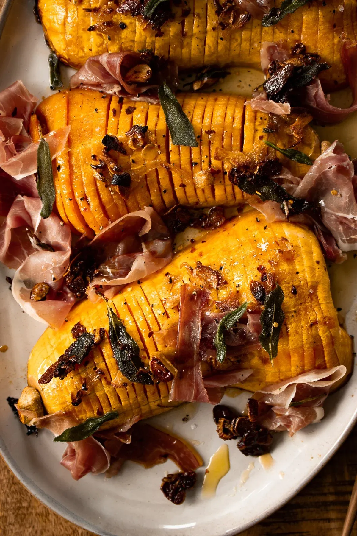Extreme close-up overhead view of two caramelized hasselback butternut squash halves showing the fine accordion-cut orange flesh in sharp detail