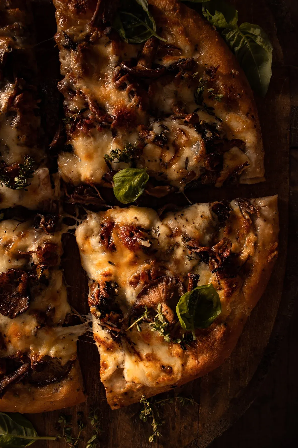 Close angled overhead view of two slices of Short Rib and Mushroom Pizza on a dark wooden board