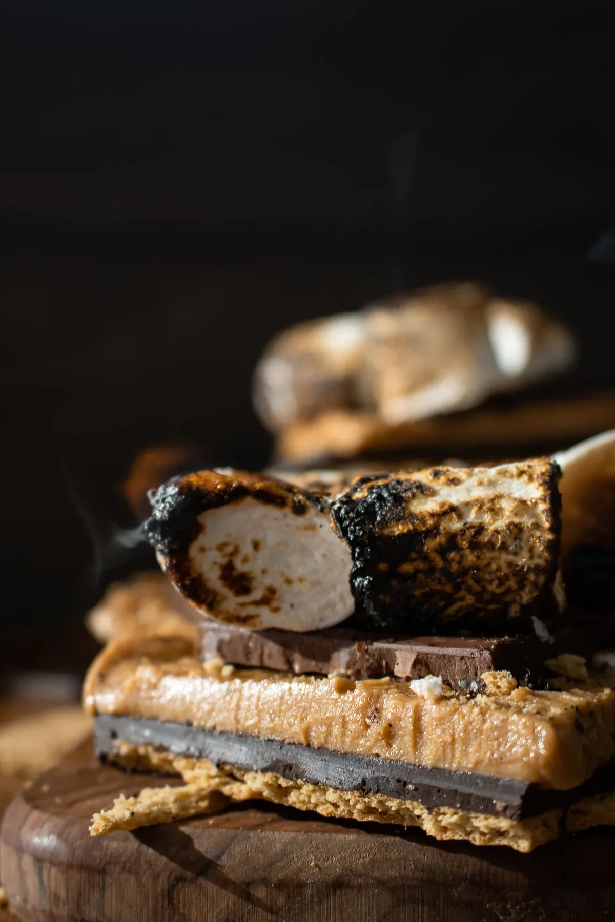 Extreme close-up side profile of a No Bake Peanut Butter and Horchata S'mores Bar stacked on a wood board