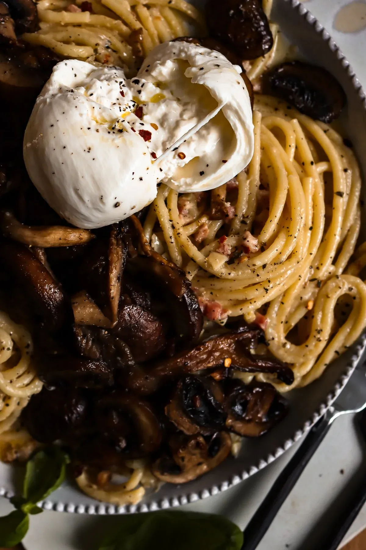 Angled close-up of the finished white wine pasta with roasted mushroom in the white beaded bowl