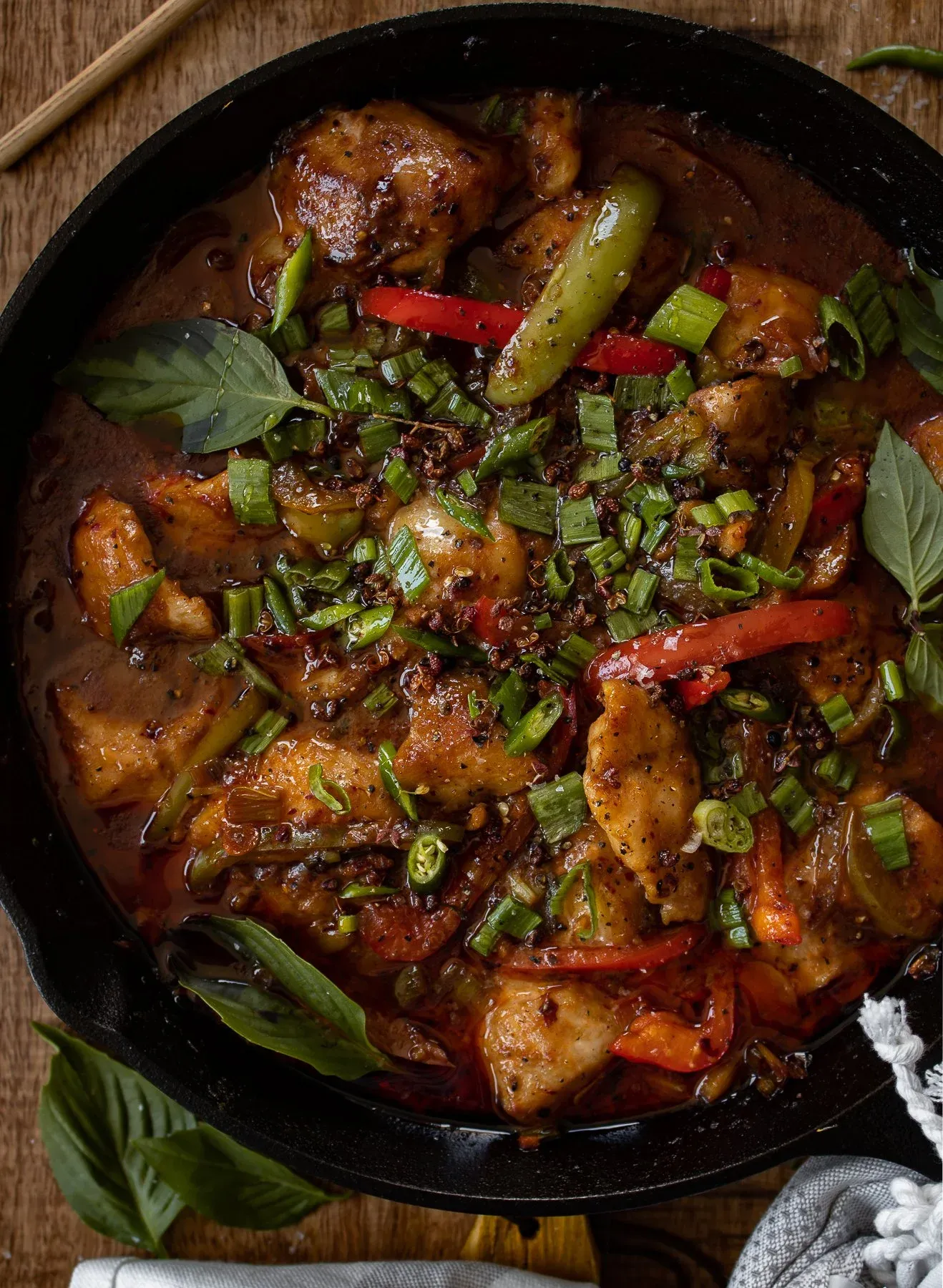 Elevated overhead shot of the entire black cast iron skillet containing Asian-inspired spicy fish