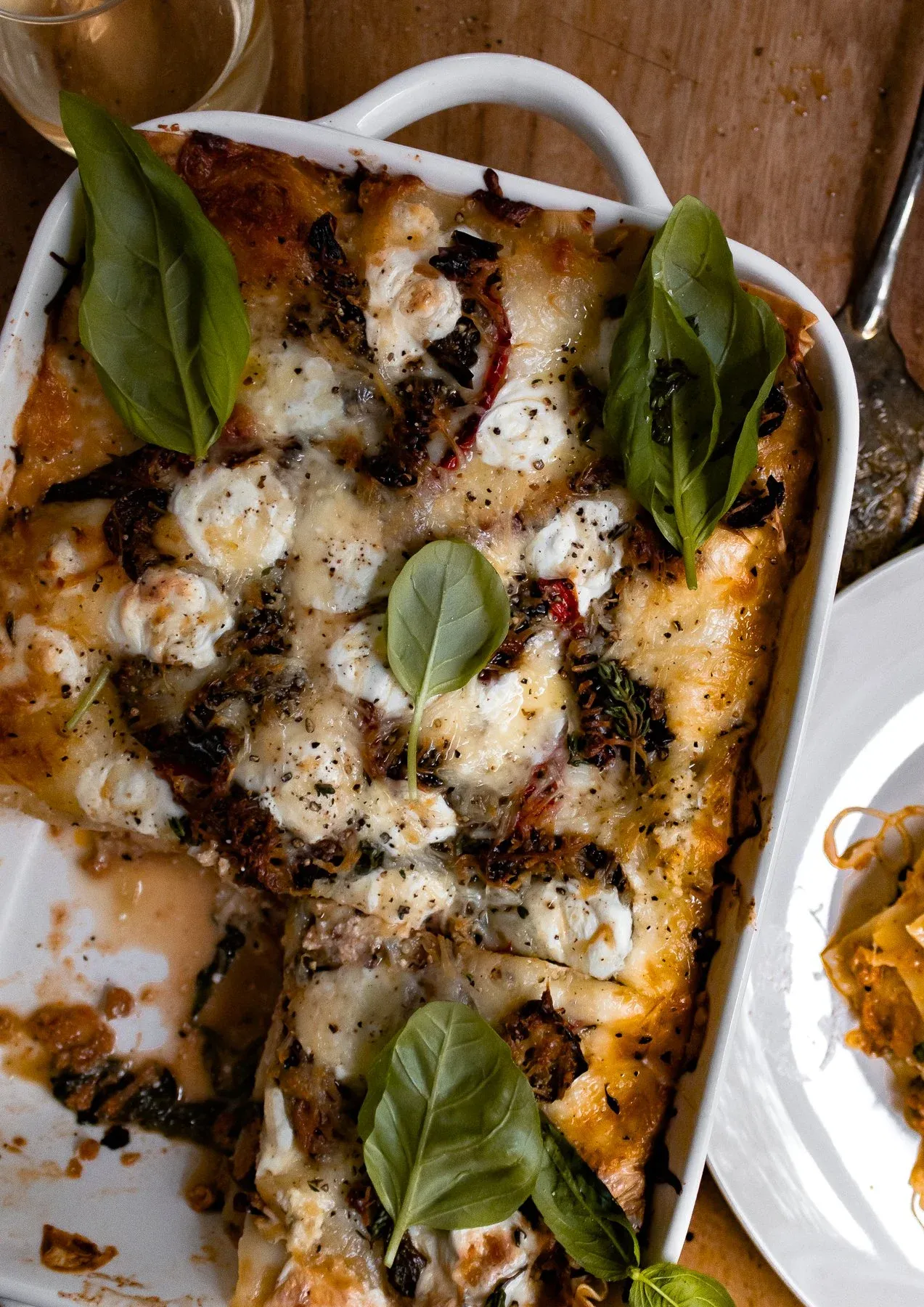 Overhead angled view of Spicy Chicken and Spinach Lasagna in a white ceramic baking dish