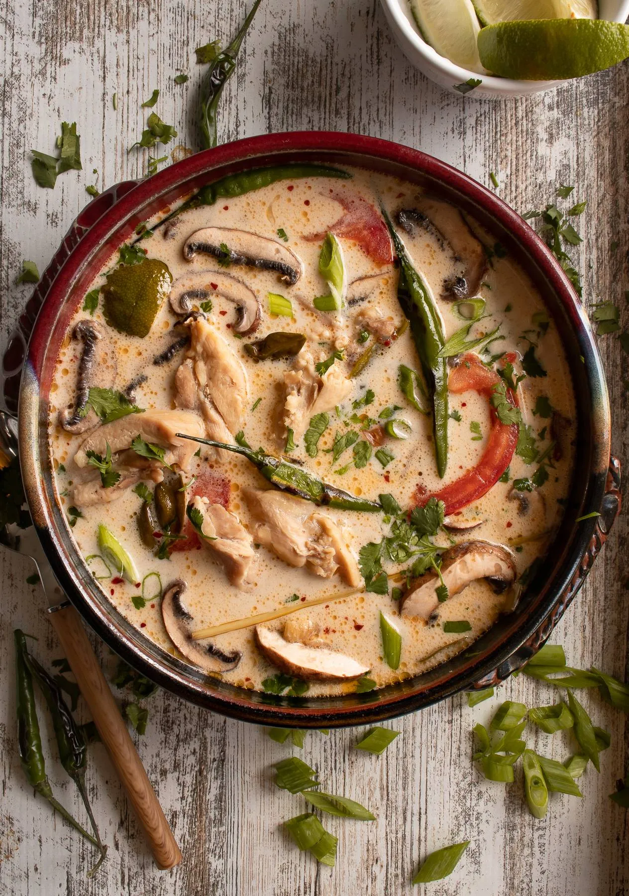 Tom Kha Gai (Thai Coconut Chicken Soup) in a large shallow copper pan with dark red rim