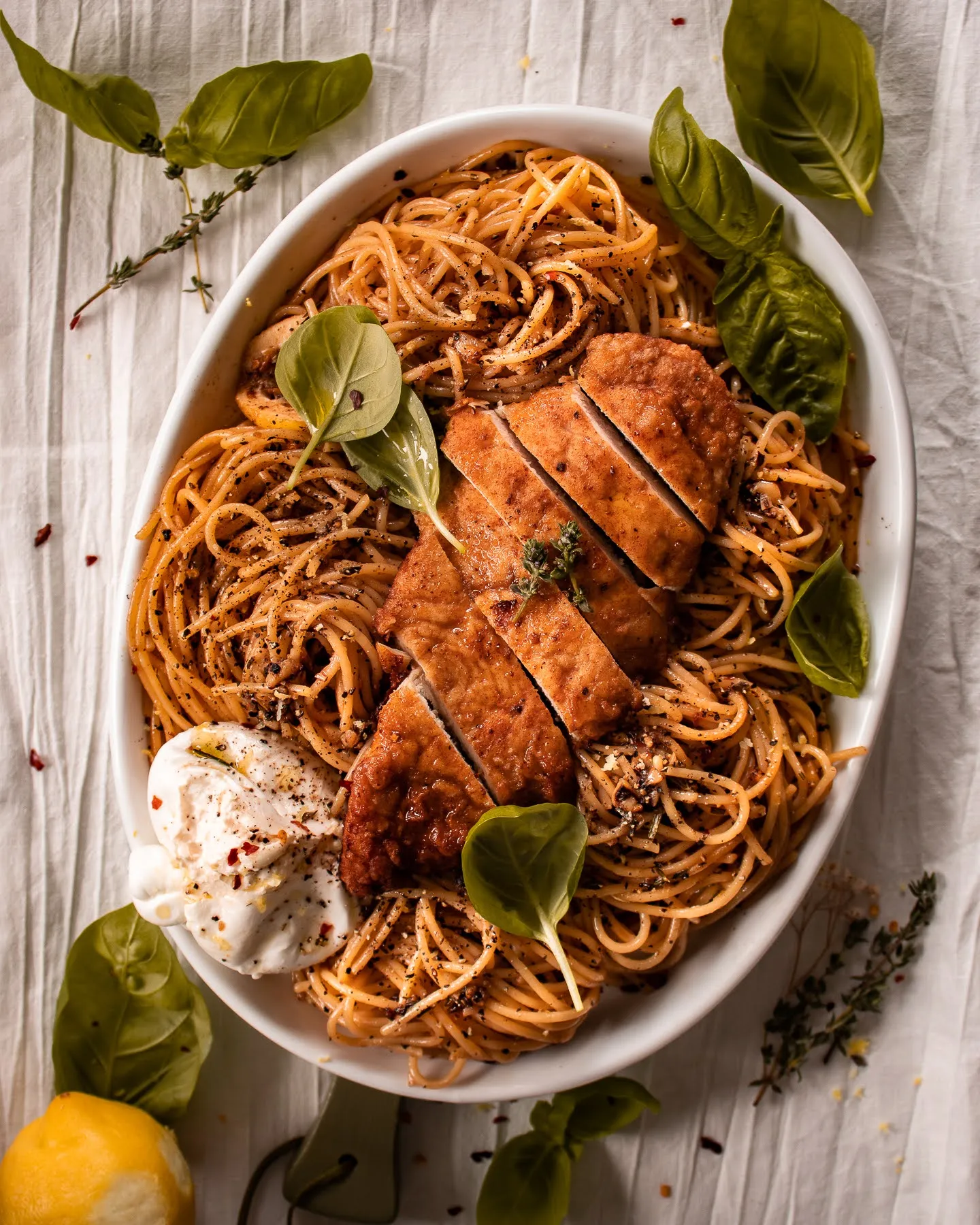 White oval serving dish of lemon pepper chicken pasta with burrata