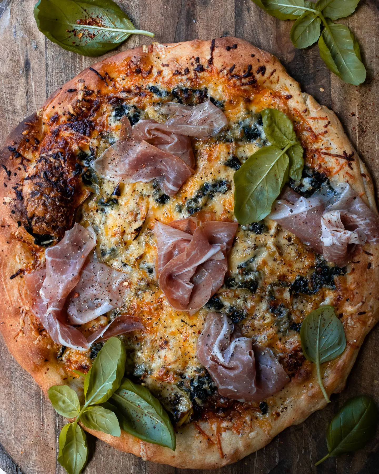 Spinach and Artichoke Pizza in a very close overhead crop on a wooden board