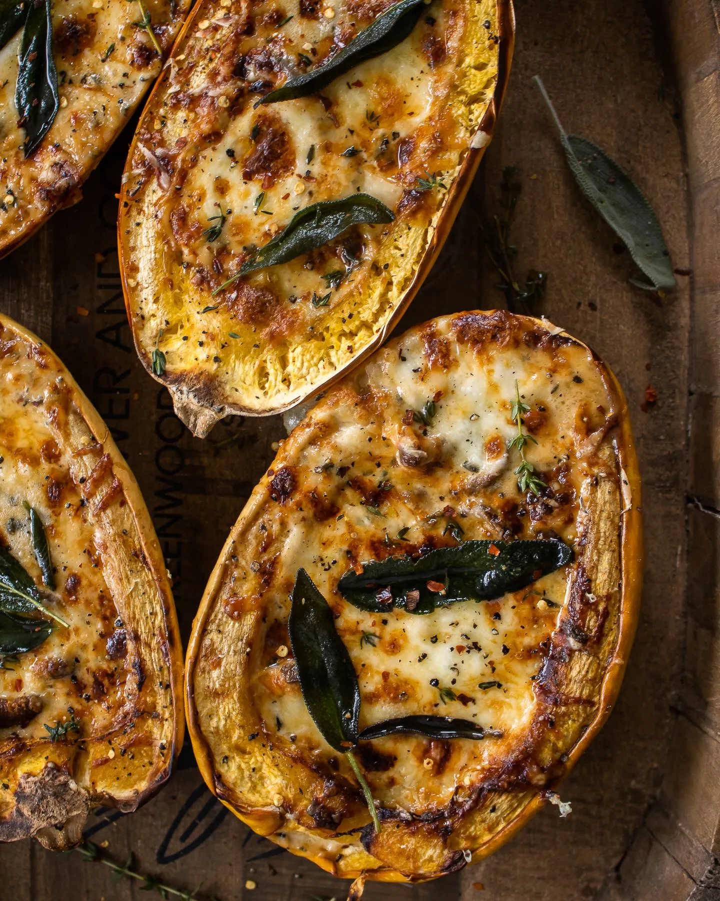 Four halved Mushroom and Sage Cream Stuffed Spaghetti Squash boats arranged on a round wooden barrel tray