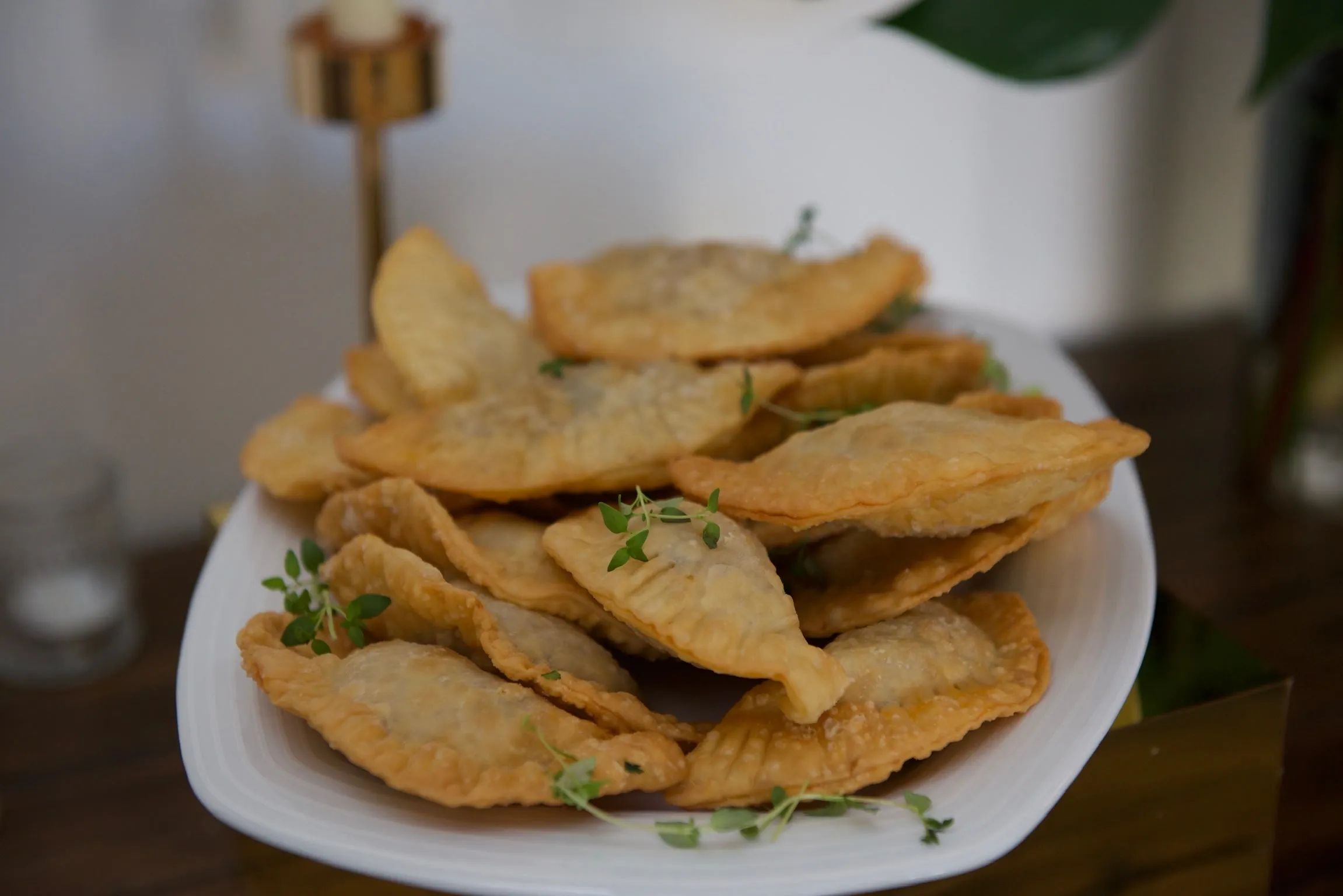 Una fuente de empanadas doradas recién fritas, con ramitas de tomillo.