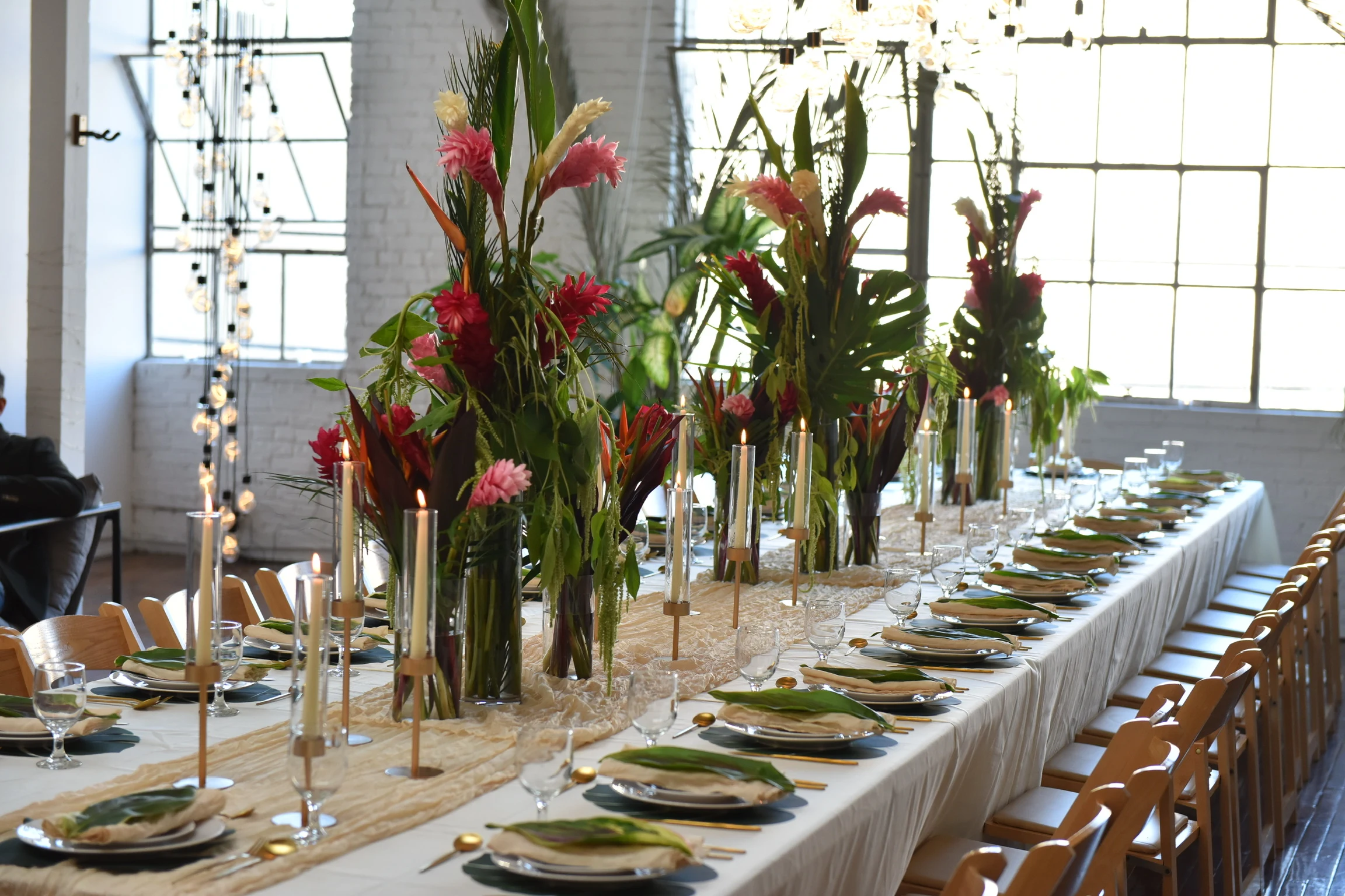 A long candlelit dinner table set with tropical flowers