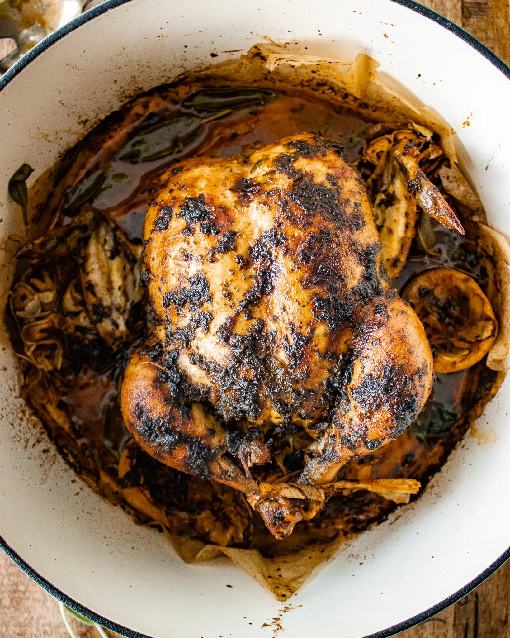 Whole Oven Roasted Chicken fresh from the pan in a round white enamel roasting dish